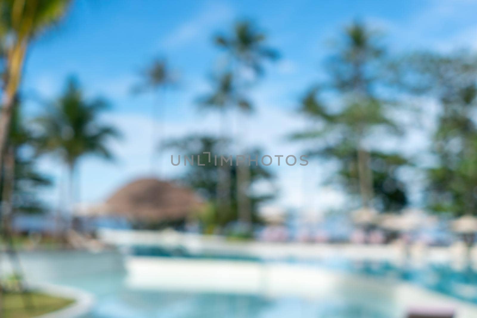 Background of a blurry resort and hotel with a swimming pool and a beach chair.