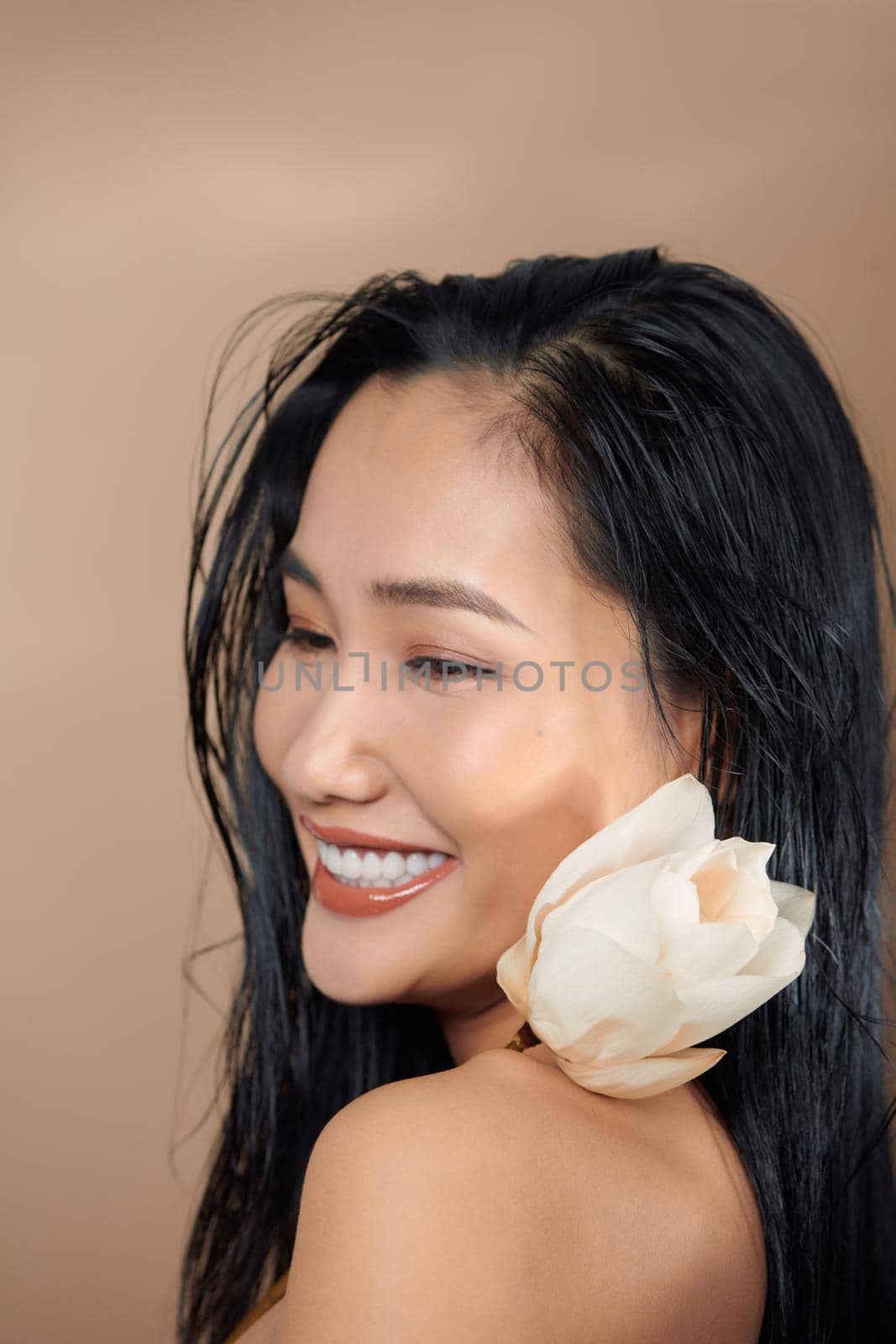 Tanned woman in white cropped top holding dried lotus buds