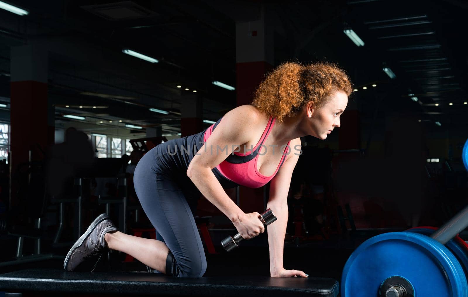 Woman bodybuilder engaged with dumbbells in the gym.