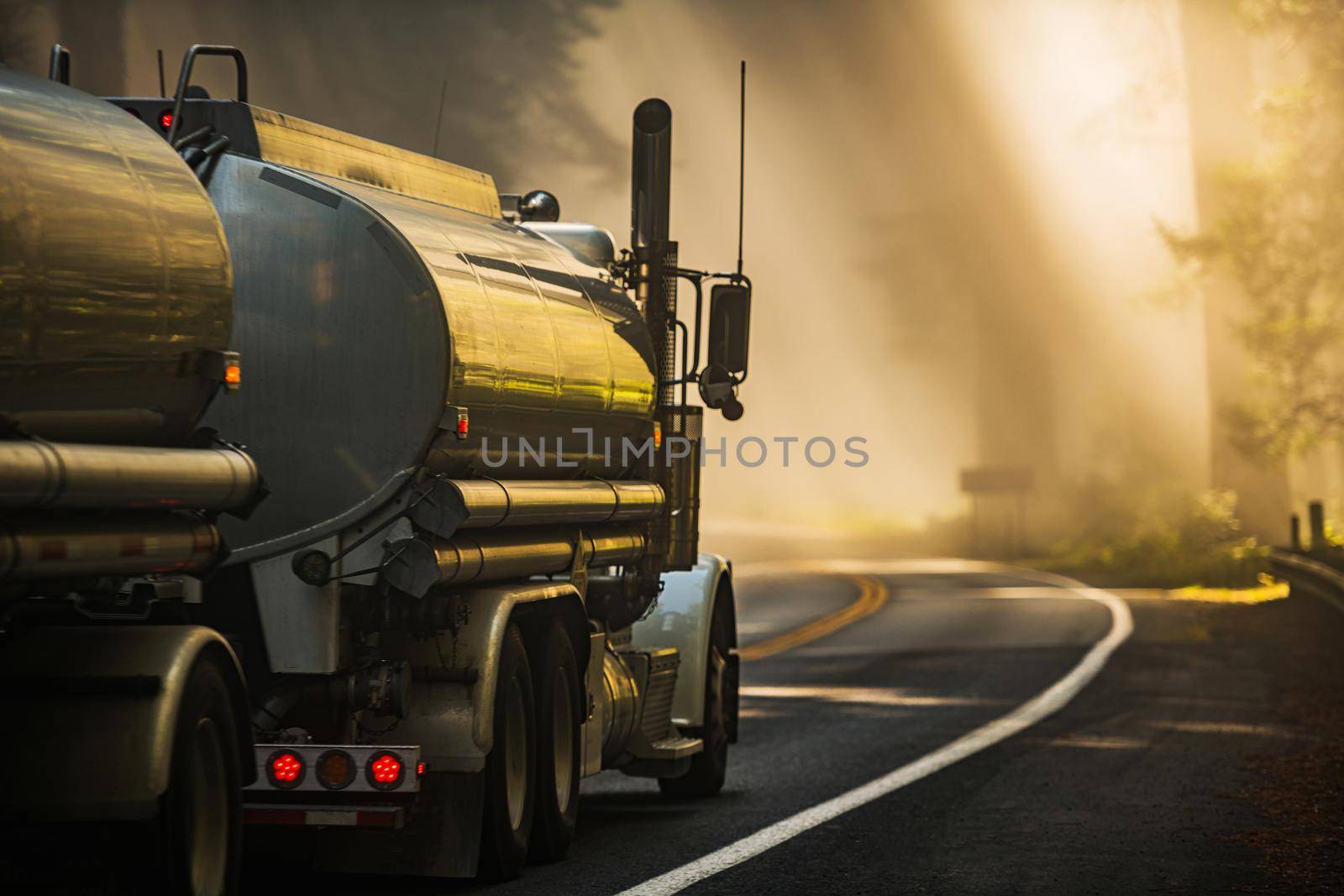 Semi Tank Truck Transporting Fuel on the Scenic Redwood Highway During Foggy Morning Scenery. Northern California Highway 101.