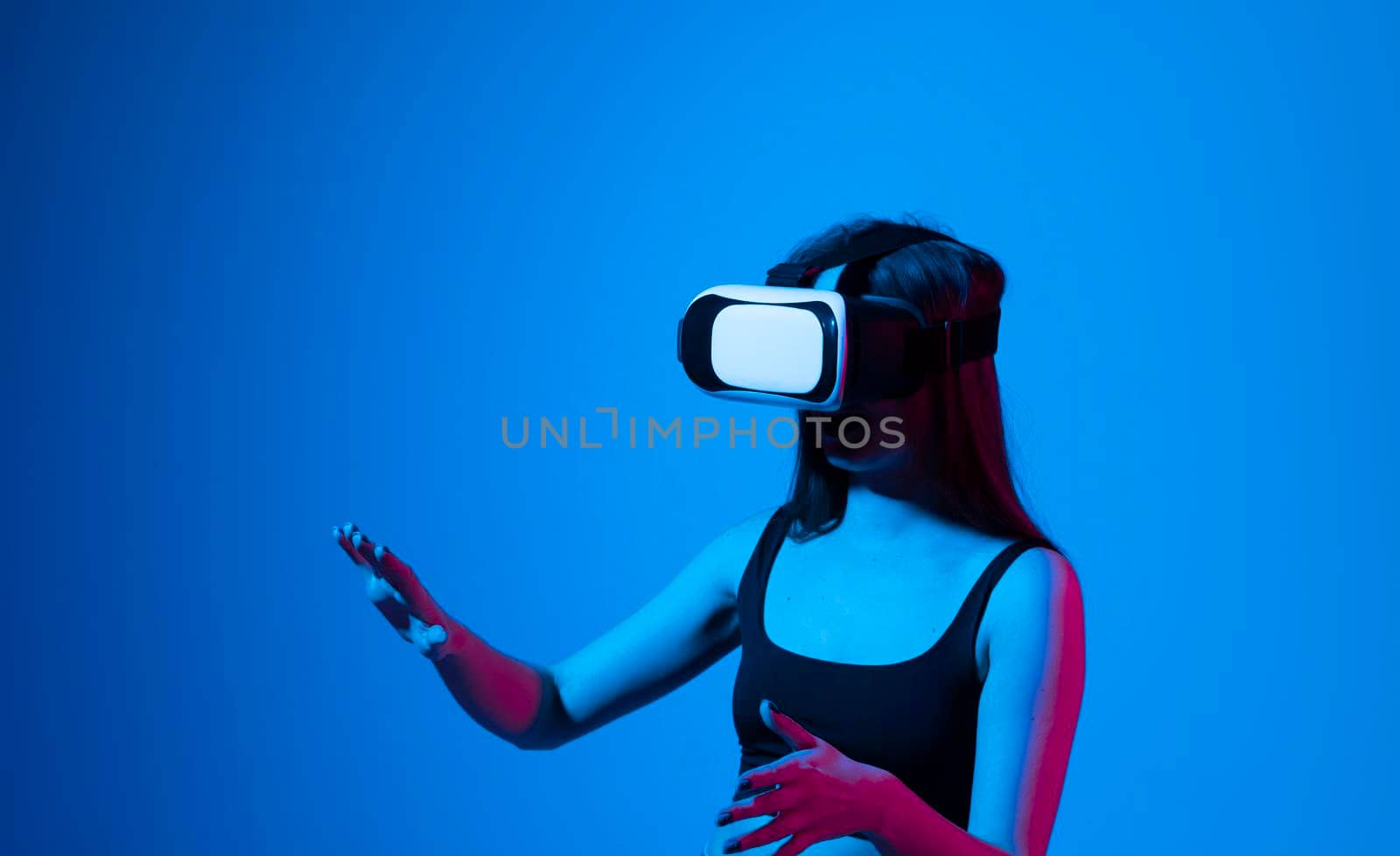 Smile happy woman getting experience using vr-headset glasses of virtual reality much gesticulating hands on gray background. Girl spend shes time in metaverse. by vovsht