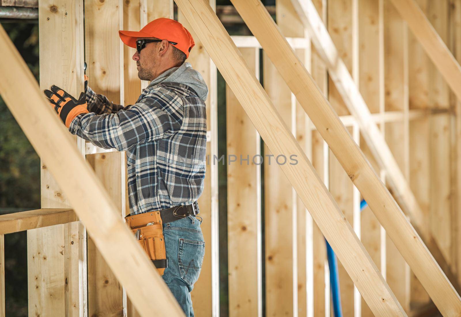 Caucasian Contractor Worker in His 30s with Drill Driver Attaching Wooden Frame Elements. Industrial Theme. Wood House Frame Construction