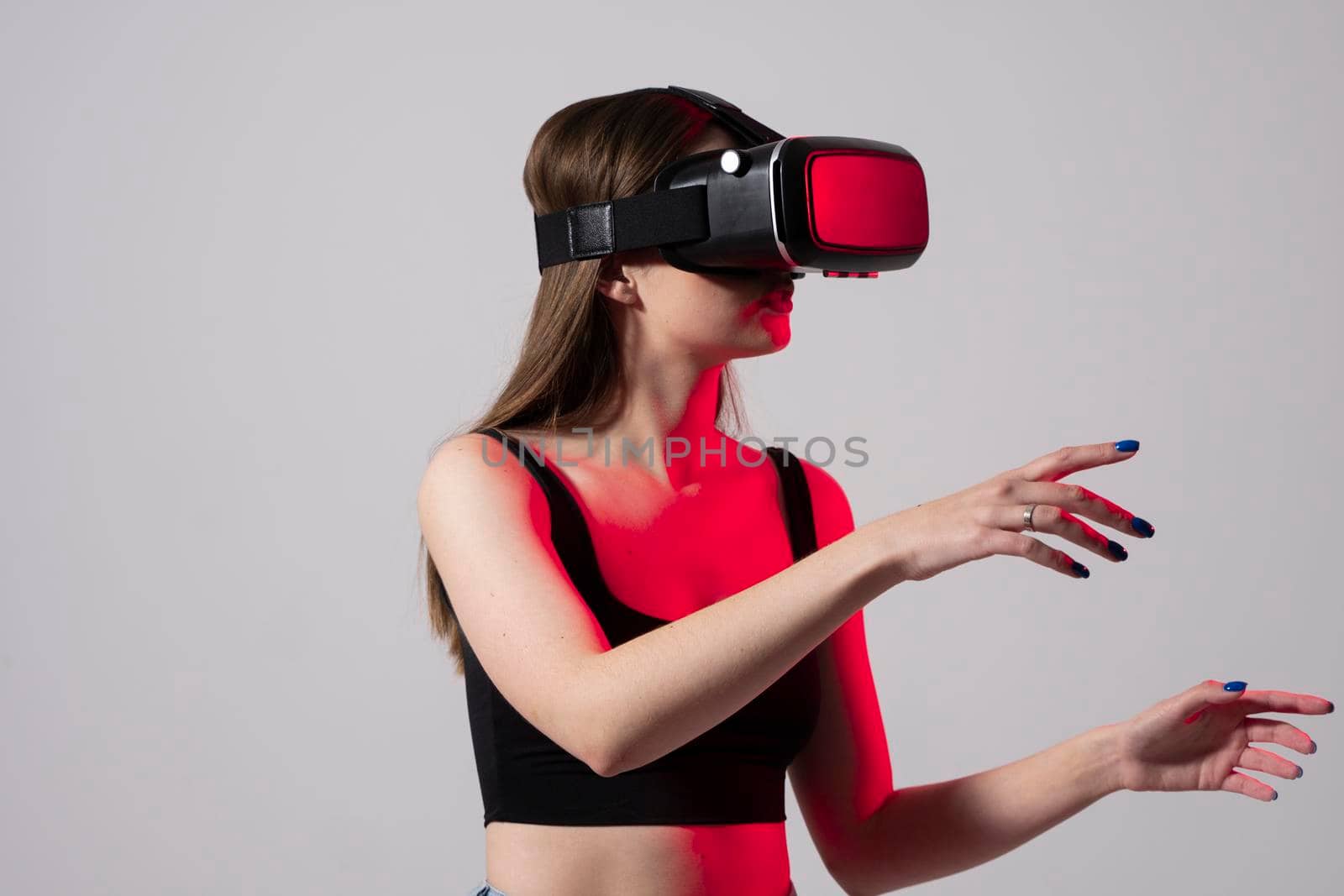 Woman using virtual reality glasses in a studio. Business woman wearing VR goggles and interacts with cyberspace using swipe and stretching gestures. by vovsht