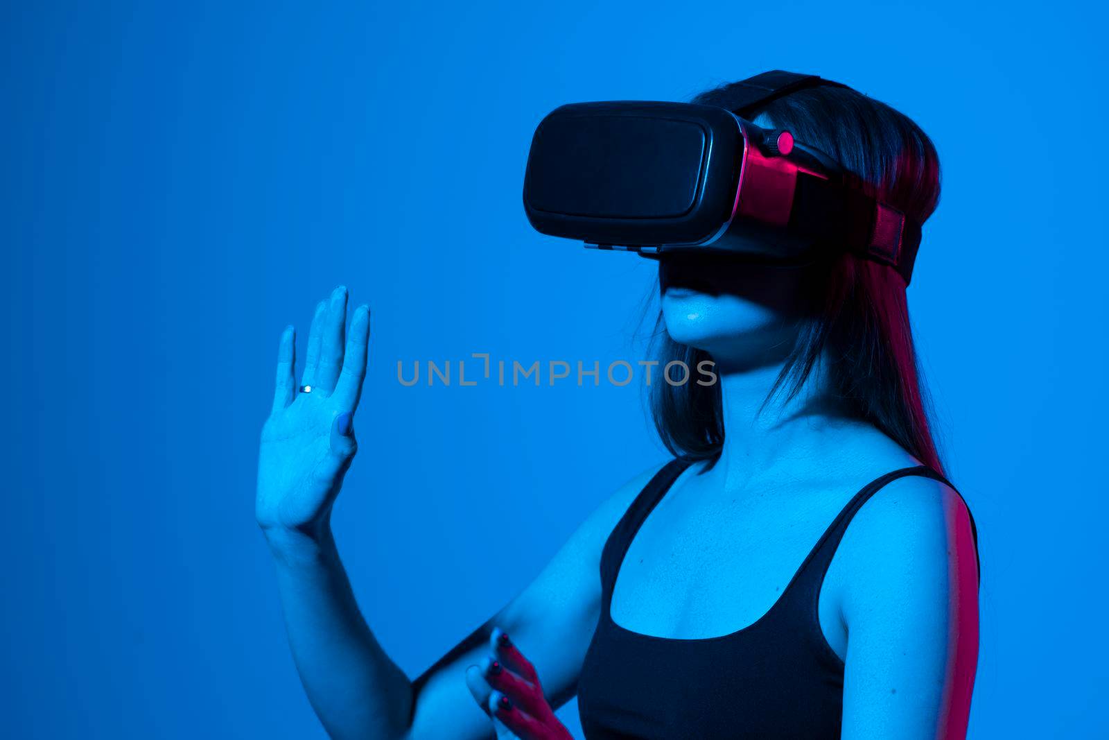 Young woman using VR headset helmet to play simulation game. Watching virtual reality 3d video. Girl in VR goggles looking around