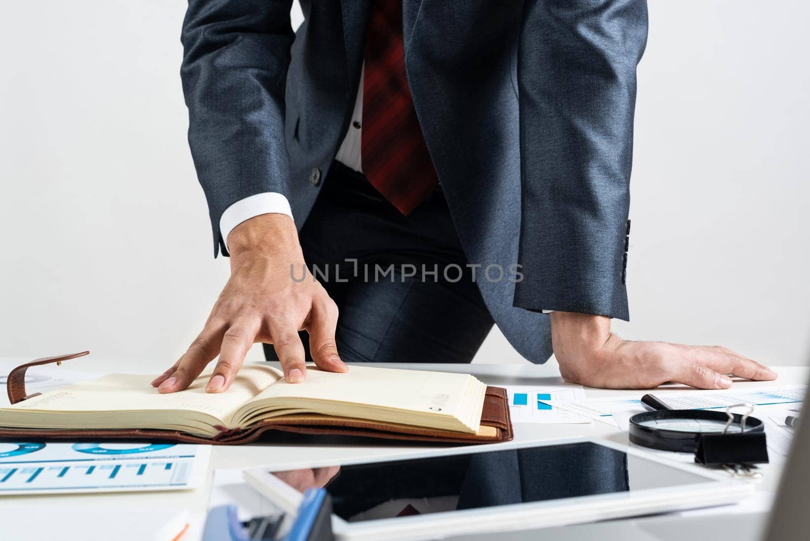 Businessman analyzing financial documents at office desk. Financial expertise and consulting. Manager in suit and tie planning day with personal organizer. Time management and work organization.