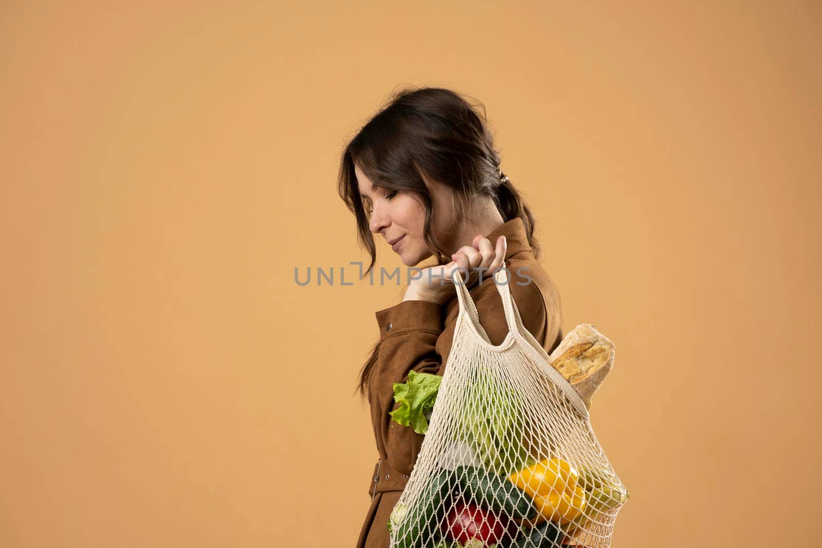 Zero waste concept. Young woman holding reusable cotton shopping mesh bag with groceries from a market. Concept of no plastic. Zero waste, plastic free. Eco friendly concept. Sustainable lifestyle. by vovsht