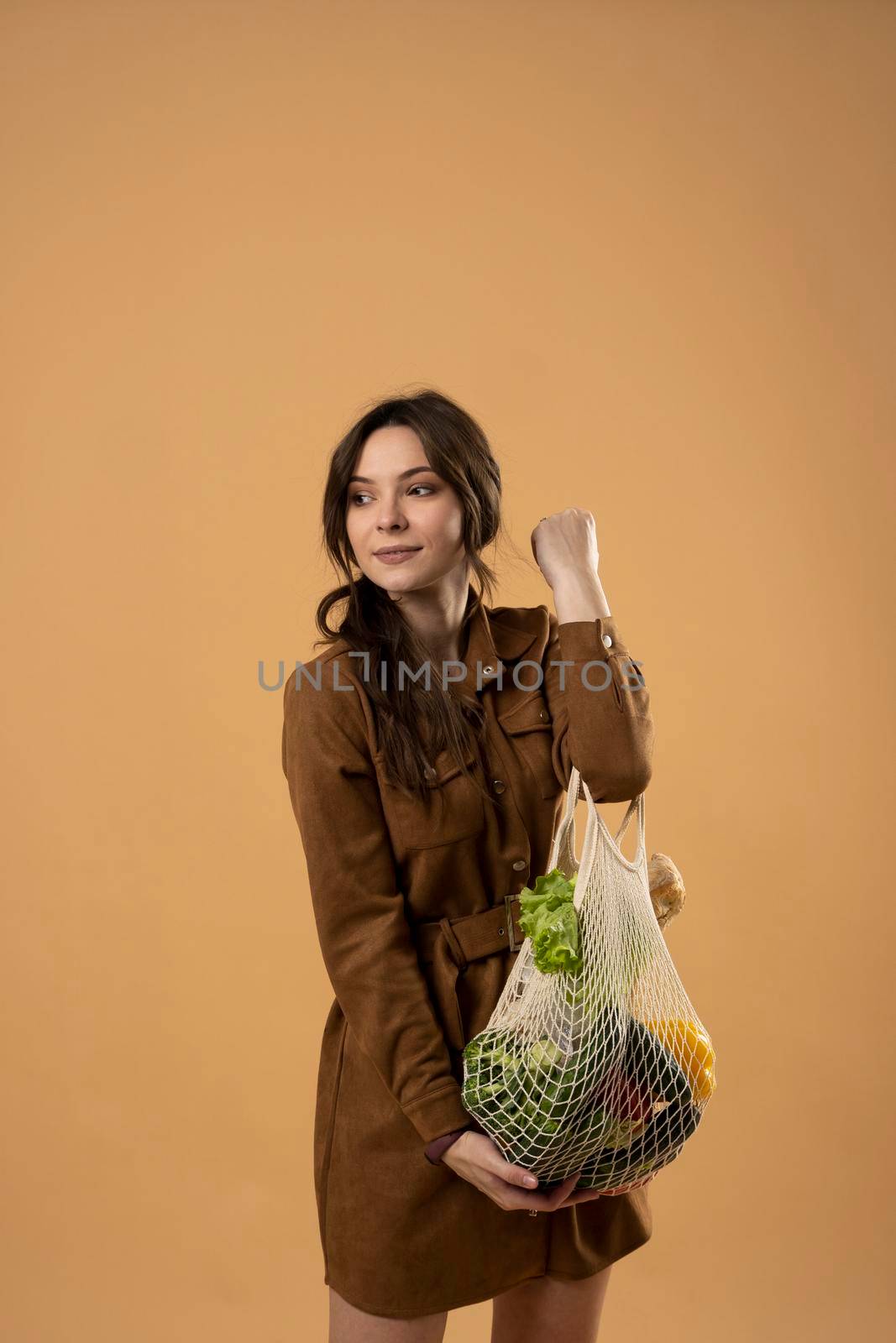 Reusable eco bag for shopping. String shopping bag with fruits and vegetables in the hands of a young woman. Zero waste, plastic free concept. Eco lifestyle. Eco shopping. by vovsht