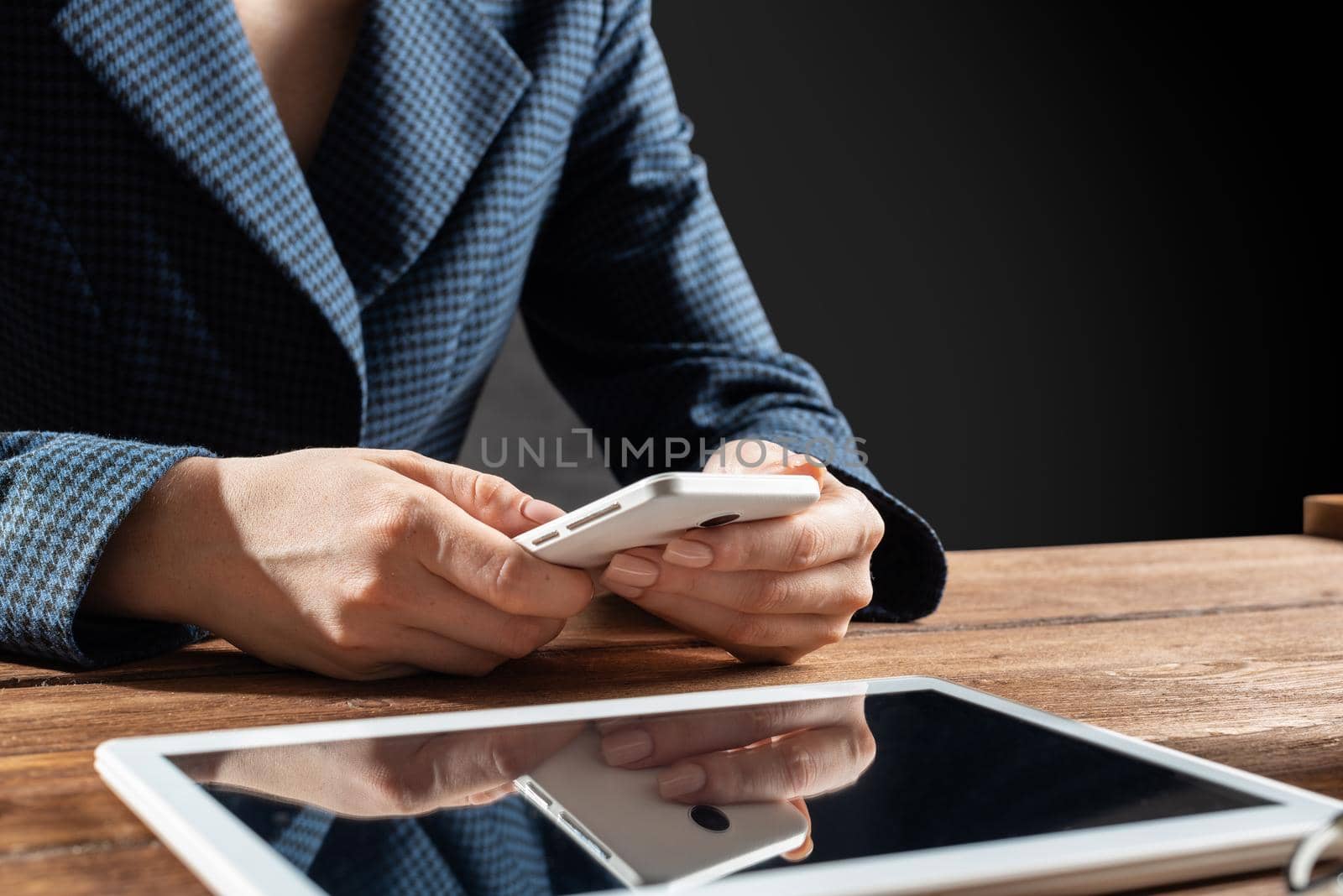 Businesswoman using mobile phone at desk. Close up woman hands and tablet computer. Mobile communication concept with chatting woman. Digital technology in strategy planning and company management