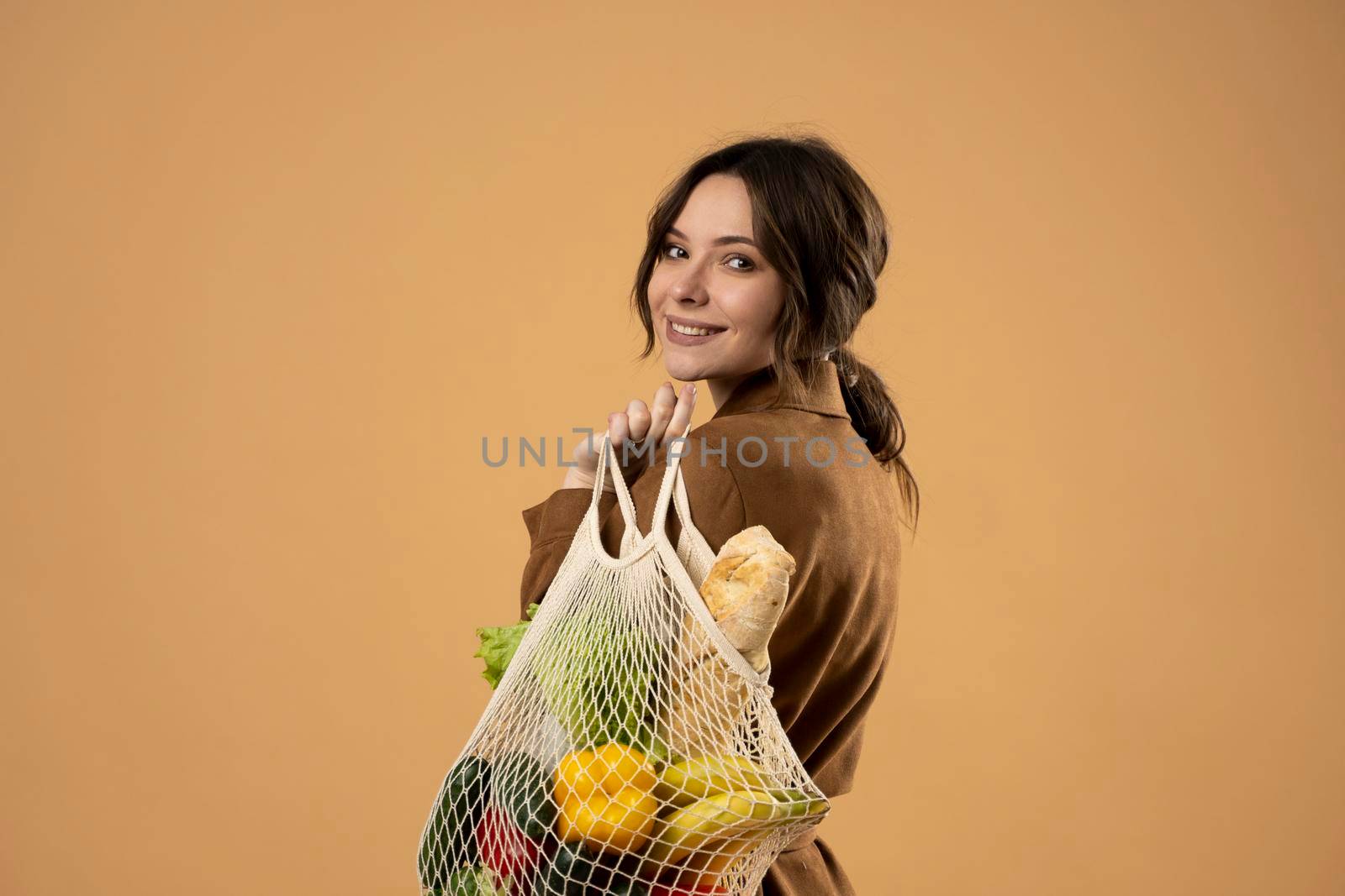 Young woman holding mesh grocery bag with vegetables Concept of no plastic. Zero waste, plastic free. Eco friendly concept. Sustainable lifestyle