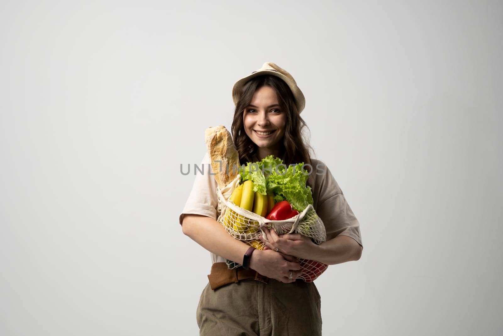 Woman holding cotton grocery bag with vegetables, greens. Reusable eco bag for shopping. Zero waste concept. Sustainable lifestyle. Eco friendly concept. by vovsht