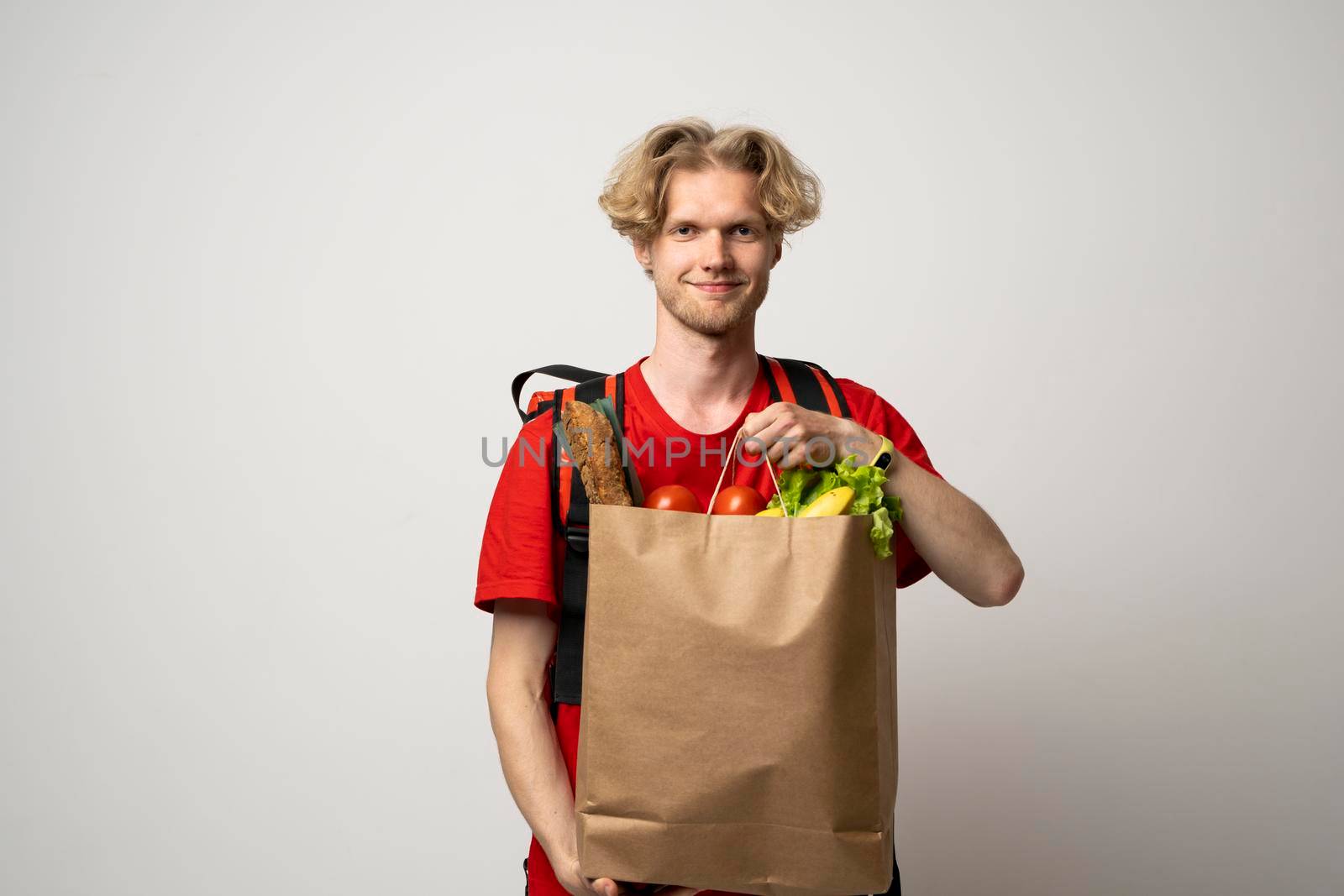 Man holding paper bag with fresh products from a groceries store on white background. Food delivery service