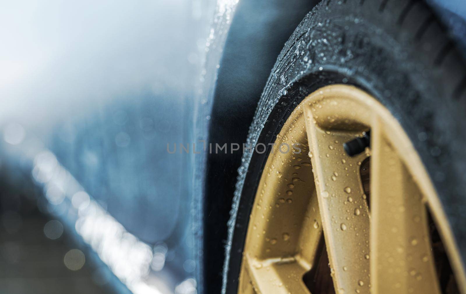 Weather Elements and the Car Wheels. Water on Elegant Golden Alloy Wheels. Transportation and Automotive Industry Theme.