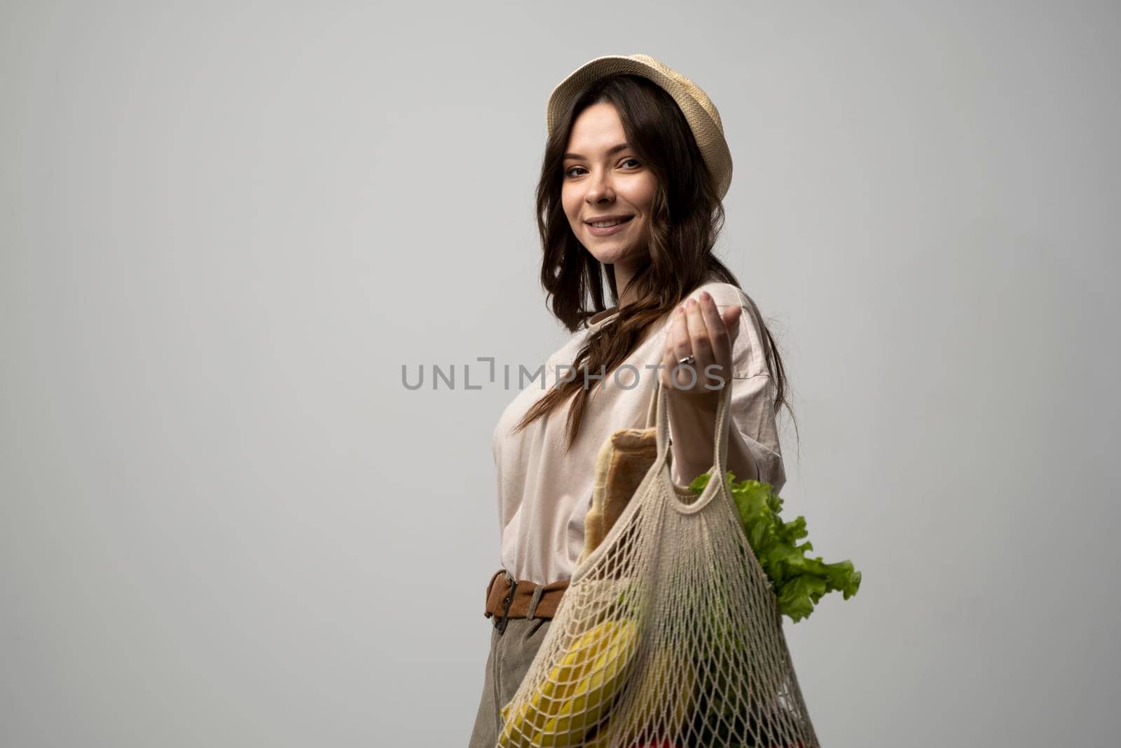 Happy brunette woman carries cotton bag full of vegetables and fruits. Zero waste concept, sustainable lifestyle, eco friendly concept, no plastic. by vovsht