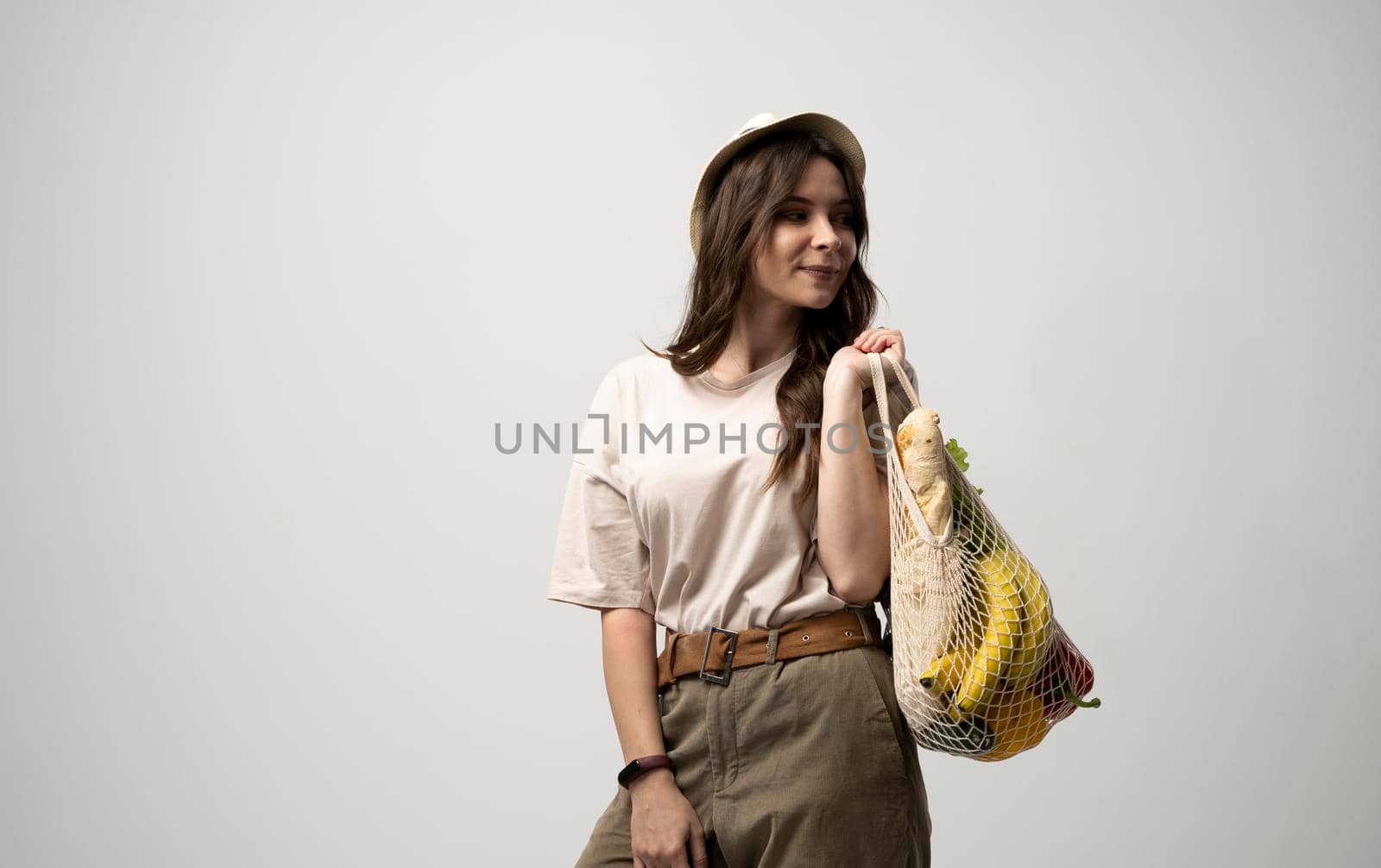 Zero waste concept. Young brunet woman holding reusable cotton shopping mesh bag with groceries from a market. Concept of no plastic. Zero waste, plastic free. Sustainable lifestyle. by vovsht
