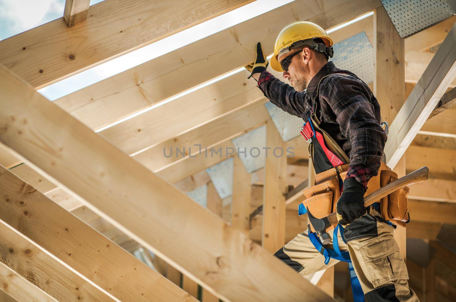 Construction Worker on Duty. Caucasian Contractor and the Wooden House Frame. Industrial Theme. by welcomia