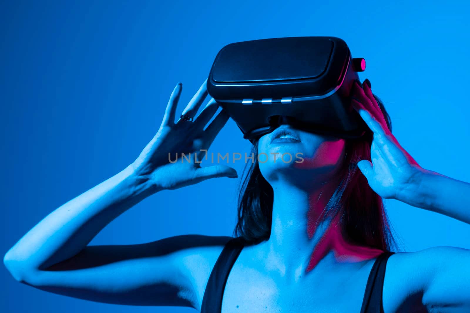 Woman enjoying a VR experience. Woman with VR headset touching invisible screen. Future technology concept