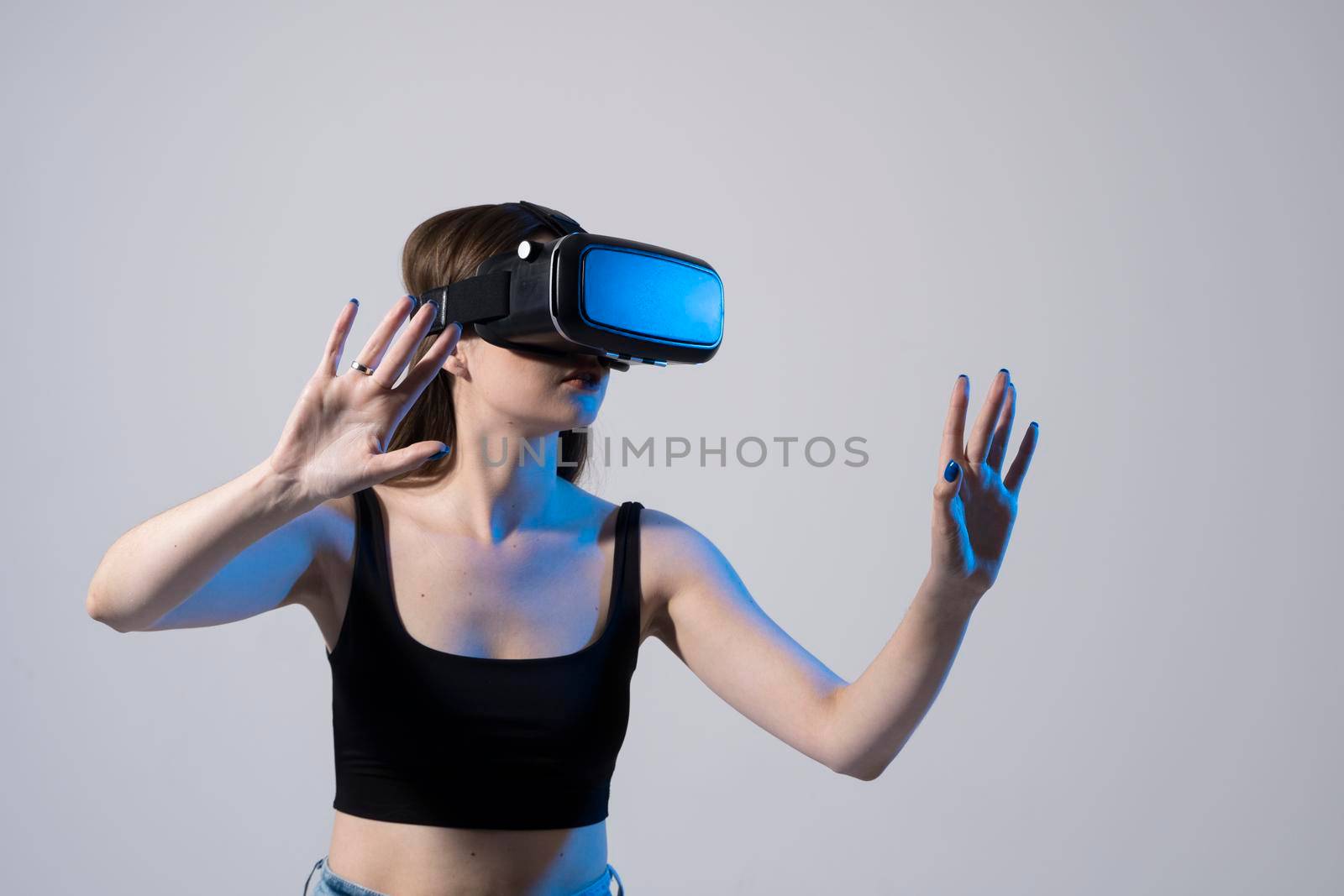 Portrait of young woman playing in VR-glasses in neon light on blue background. Concept modern gadgets and technologies. Future technology concept. Virtual reality gaming