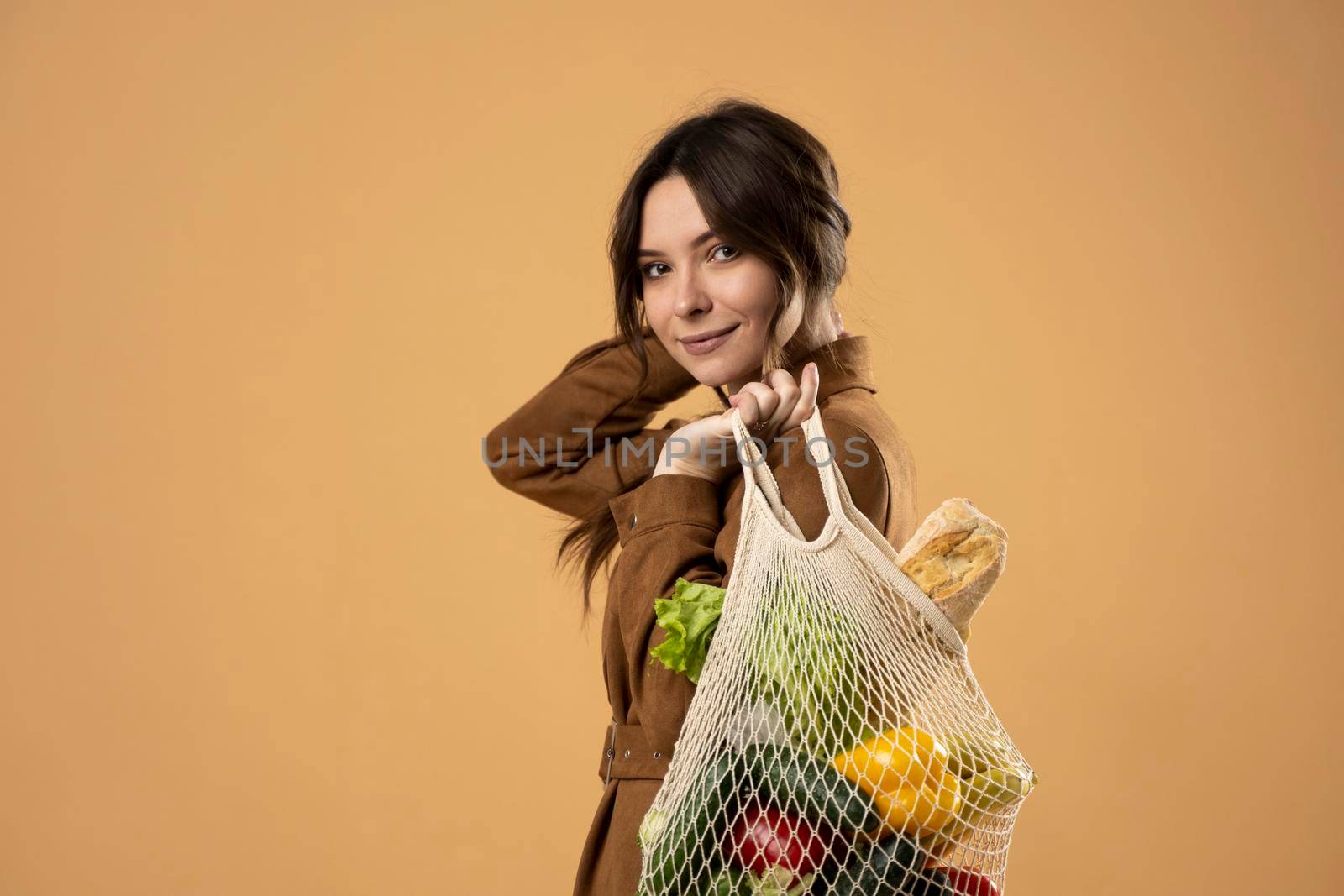 Zero waste concept. A young brunete girl holds on her shoulder a textile eco bag with groceries. Plastic free concept. Eco lifestyle. Eco shopping. Conscious consumption. Eco trend