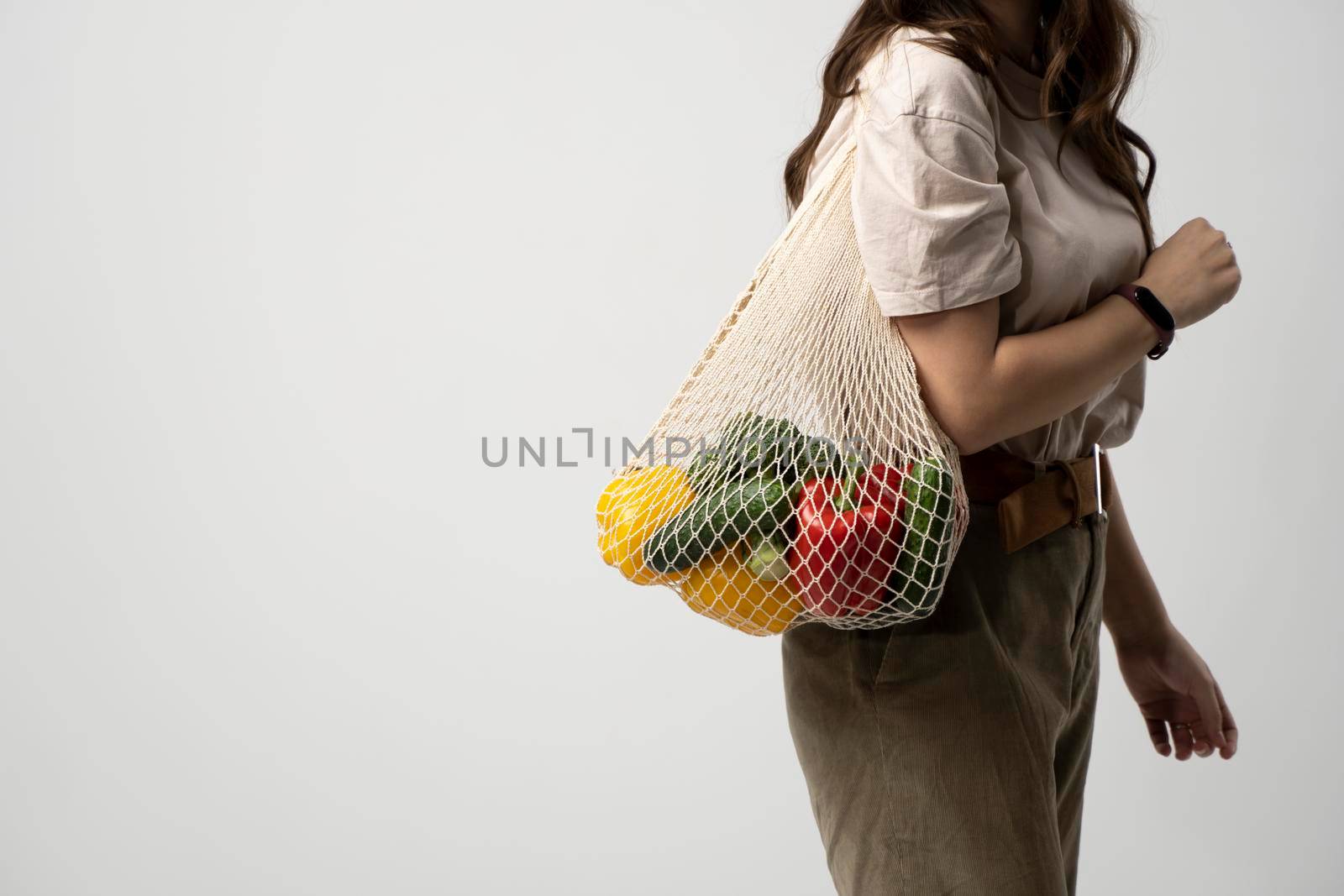 Reusable eco bag for shopping. String shopping bag with fruits and vegetables in the hands of a young woman. Zero waste, plastic free concept. Eco lifestyle. Eco shopping