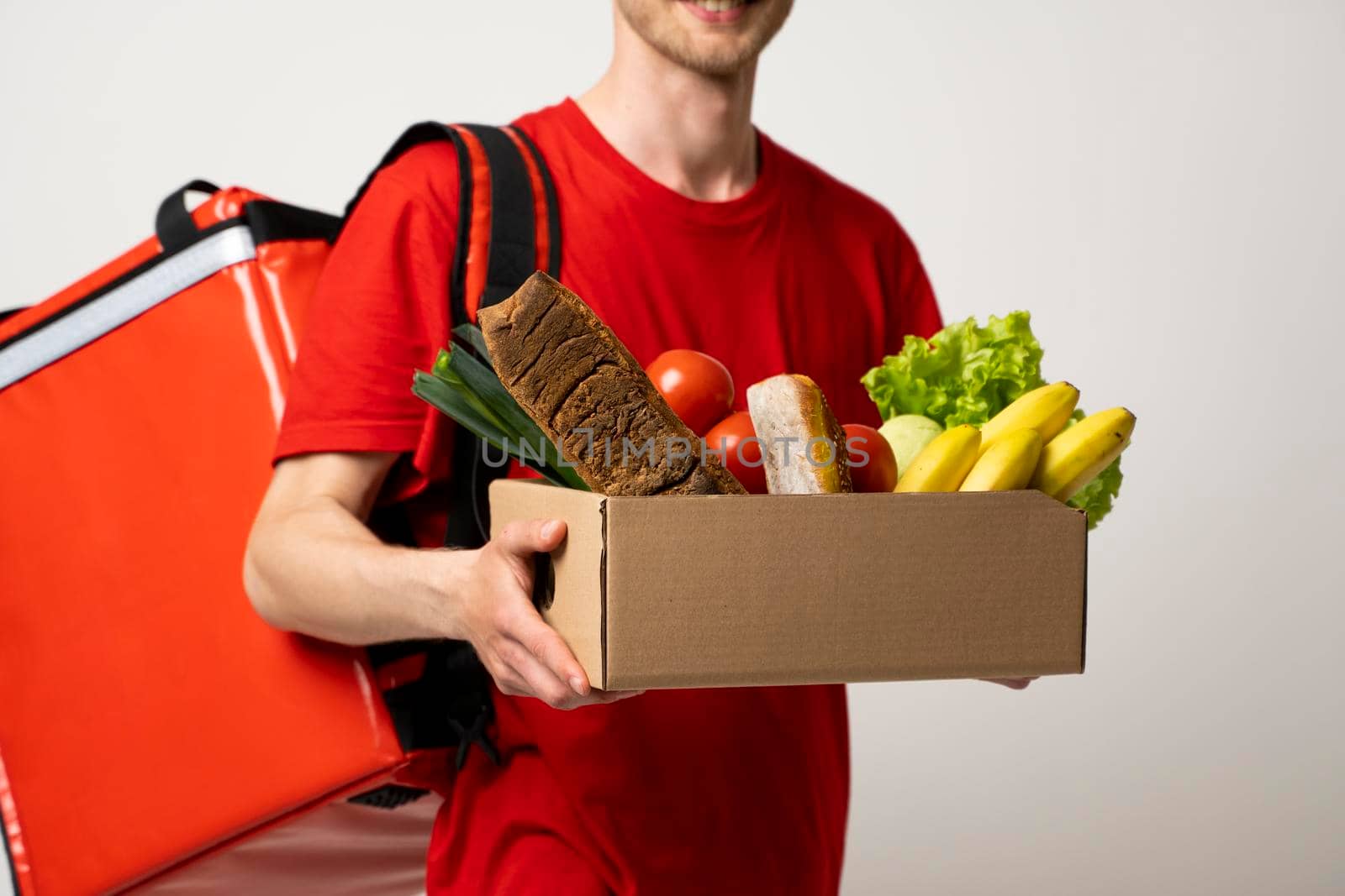 Delivery Concept - Handsome delivery man carrying package box of grocery food and drink from store. by vovsht