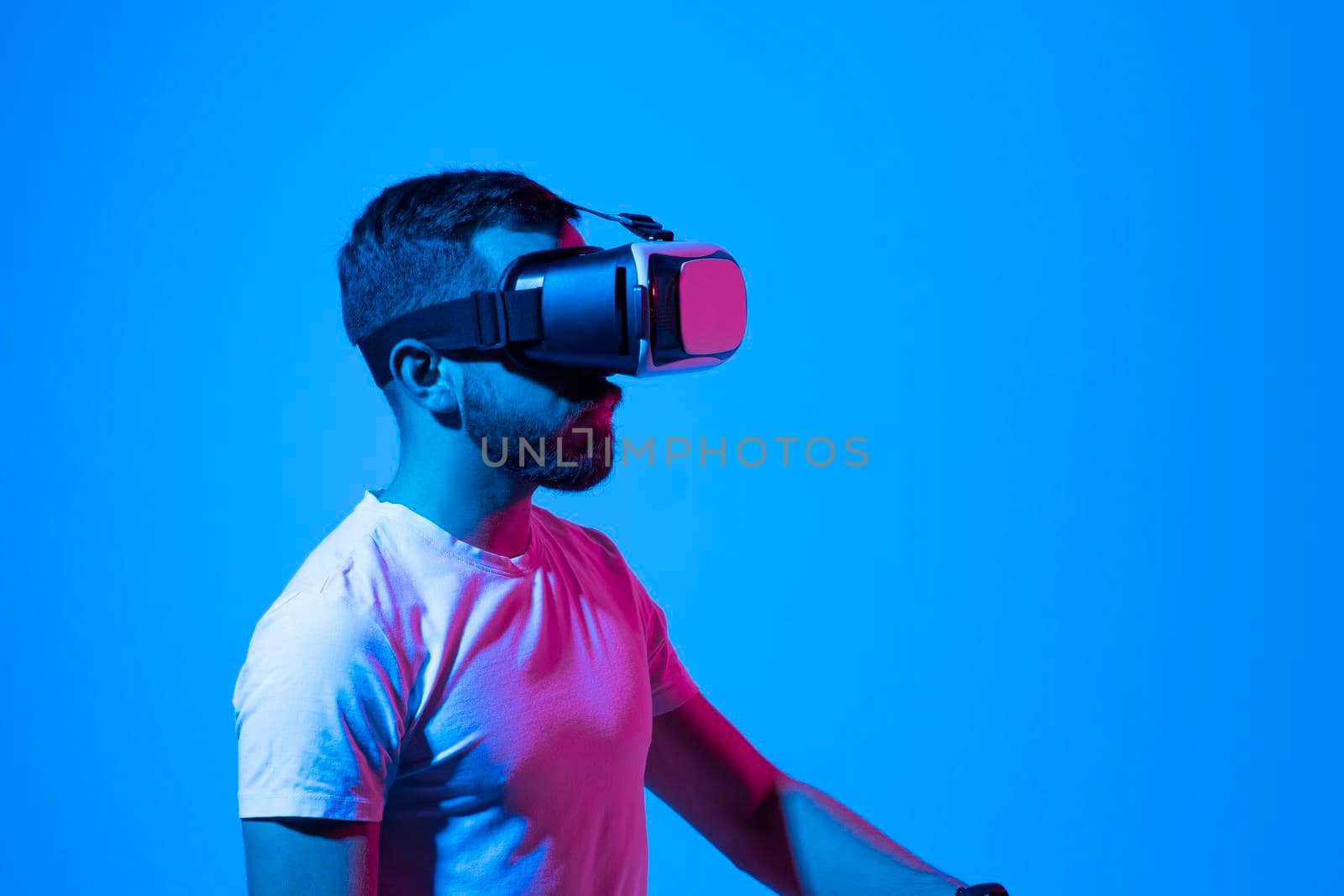 Bearded young man wearing virtual reality goggles and interacting with a virtual environment. Future technology concept. Metaverse