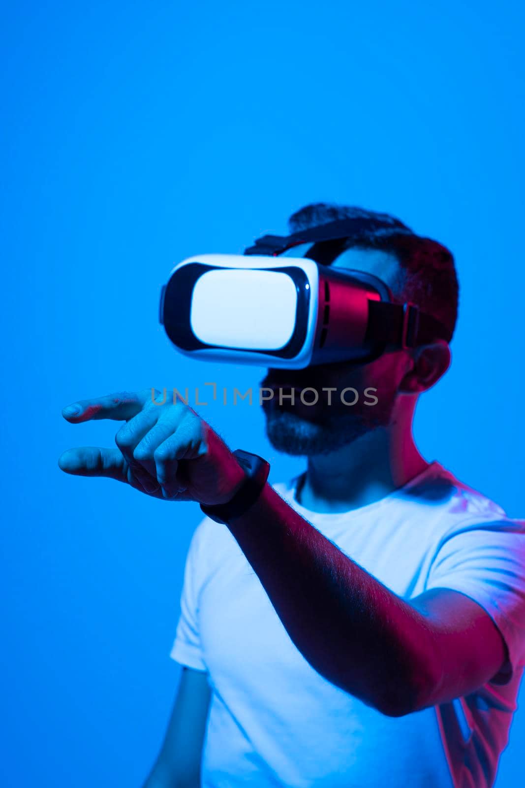 Handsome young man in VR headset is gesturing and try to touch to something that he see. Virtual reality concept