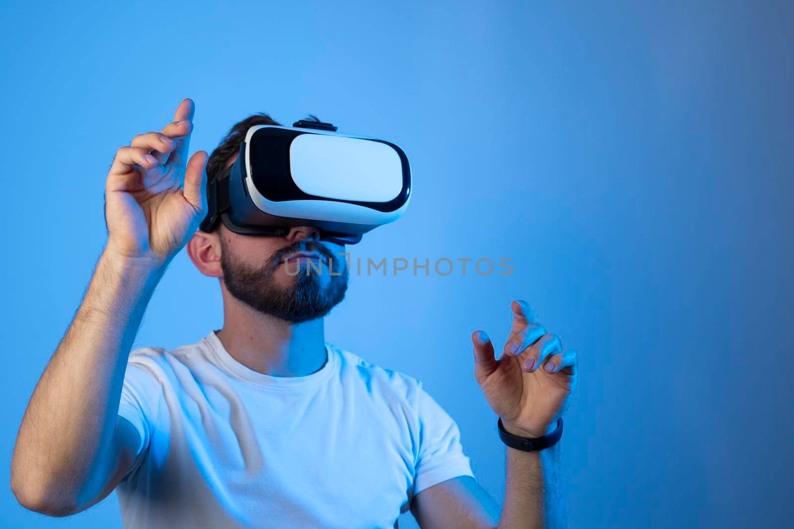 Bearded man using VR headset helmet to interacts with metaverse using swipe and stretching gestures. Watching virtual reality 3d video. Man in VR goggles looking around