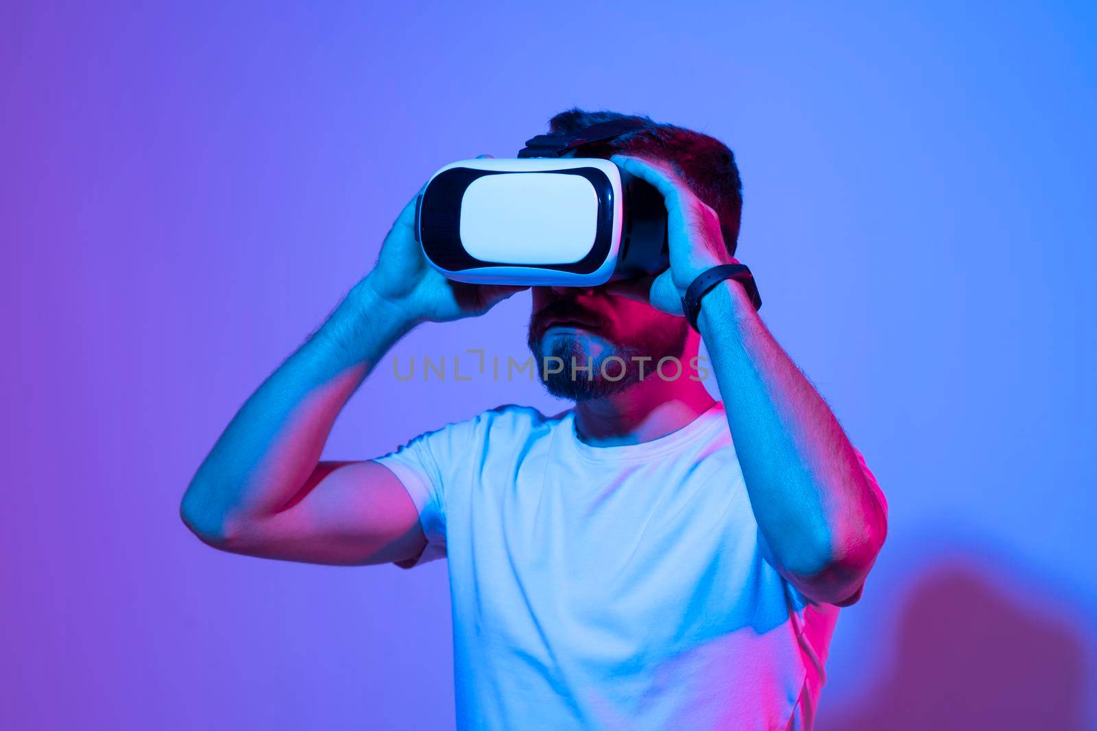 Closeup of young man wearing virtual reality goggles in modern studio. Smartphone using with VR headset. by vovsht