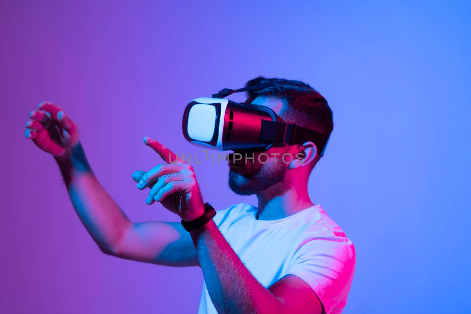 Bearded man playing VR video game in metaverse with virtual reality goggles and trying to touch something. Future technology concept