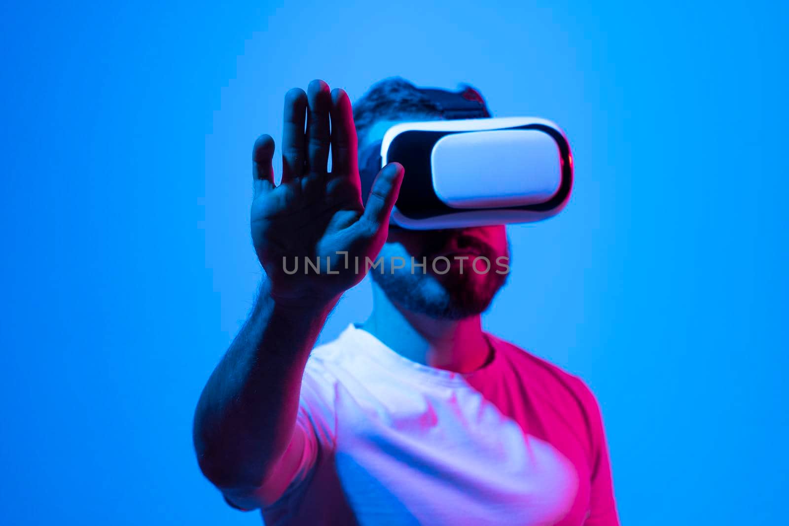 Amazed young bearded man, wearing high tech smart vr goggles, watching 360 degree video or playing a video game in metaverse. by vovsht