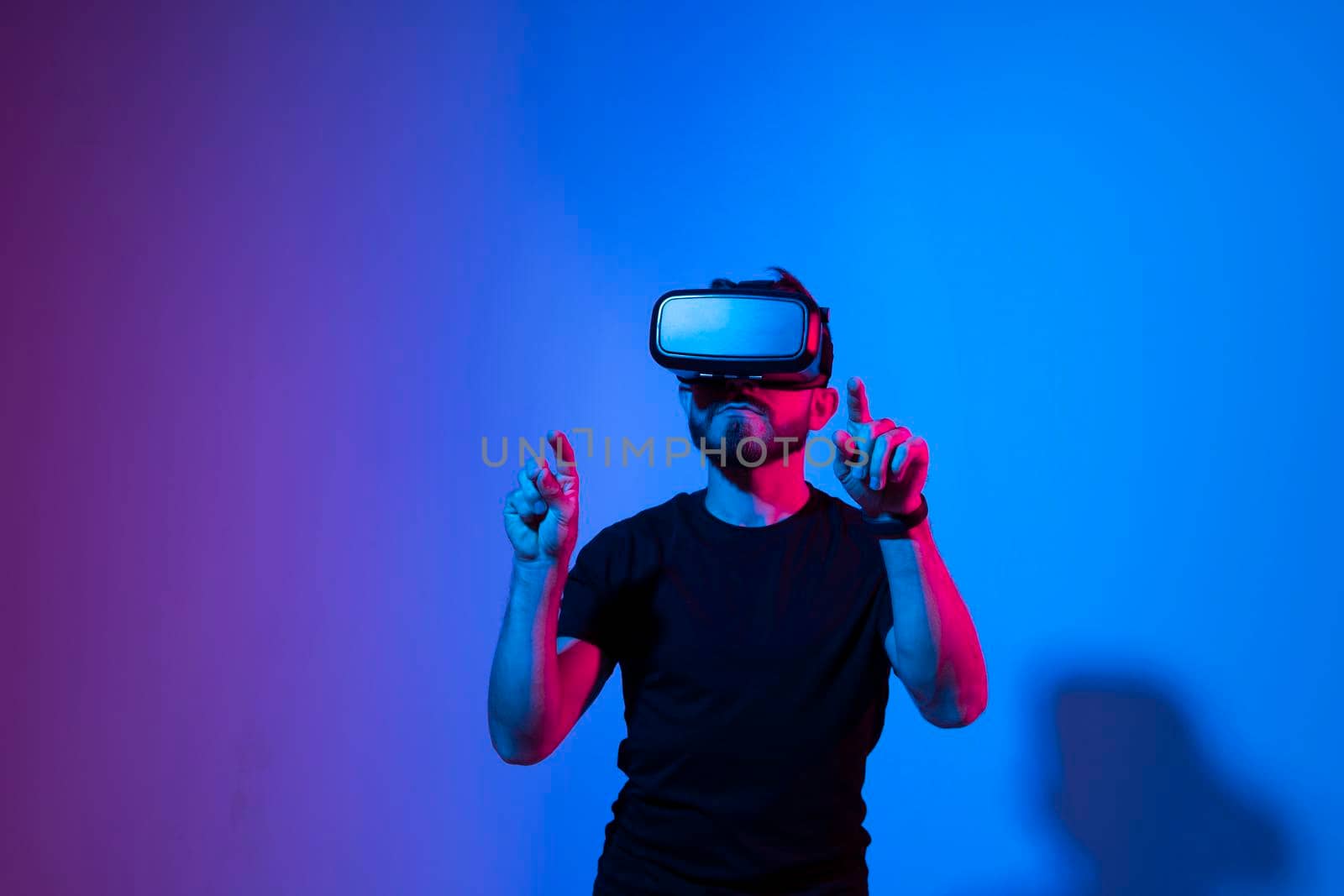 Future technology, gaming, entertainment and people concept - happy young man with virtual reality headset or 3d glasses playing video game in metaverse. by vovsht