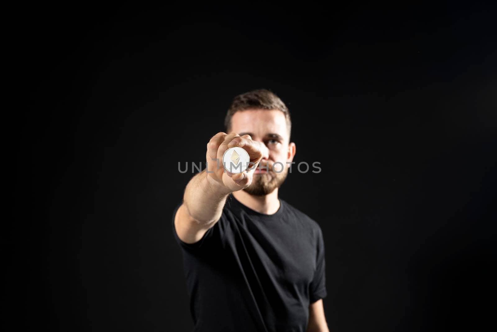 Young bearded man holding virtual currency ethereum coin and bitcoin. Cryptocurrency