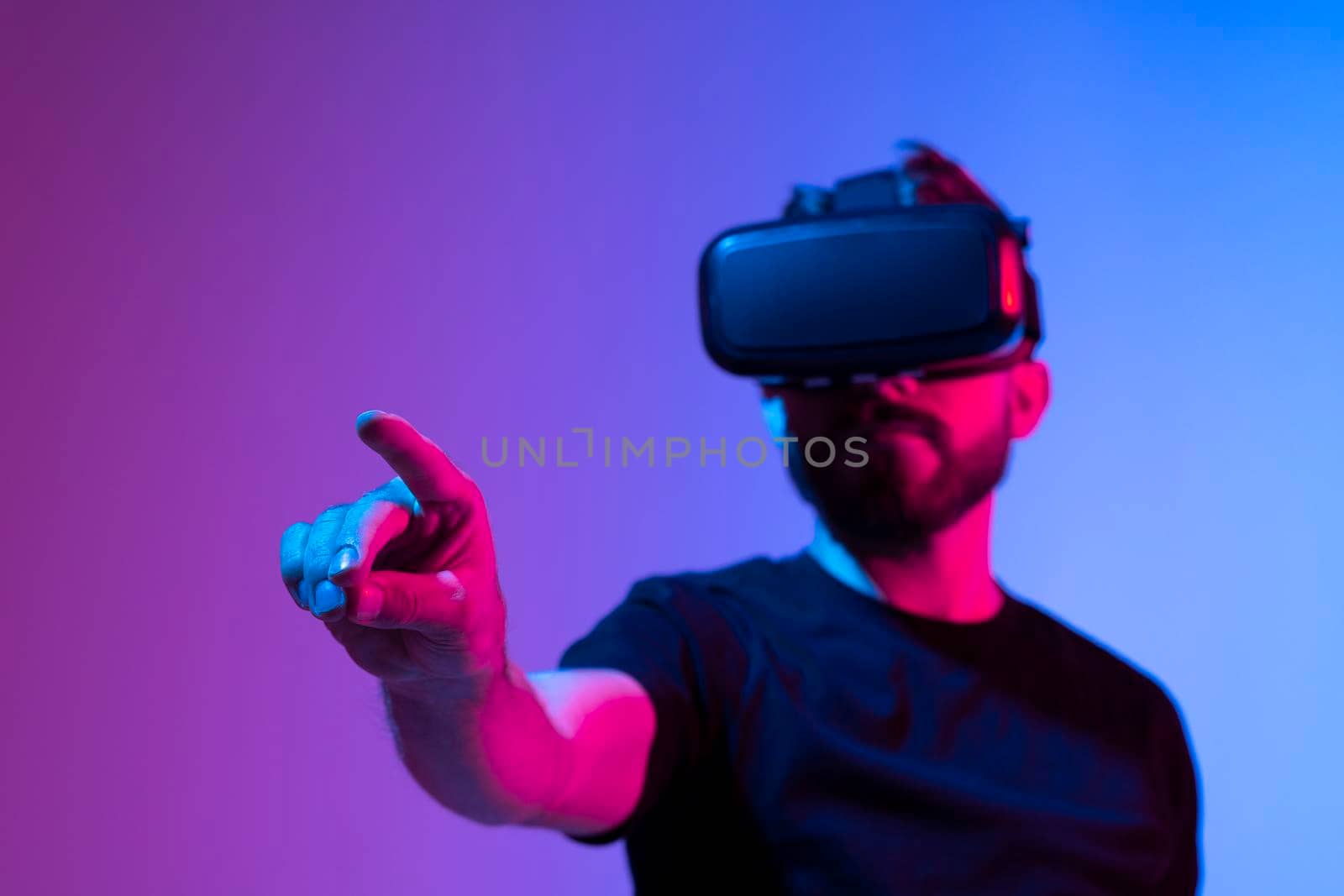 Amazed young bearded man, wearing high tech smart vr goggles, watching 360 degree video or playing a video game in metaverse