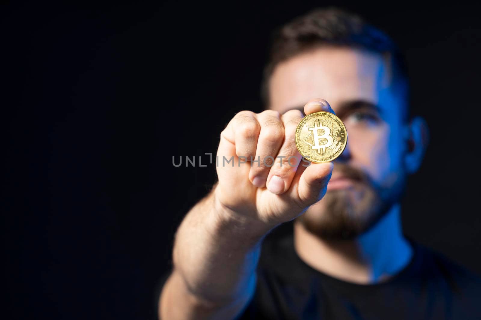 Confident young business man wearing black with a bitcoin in a hand