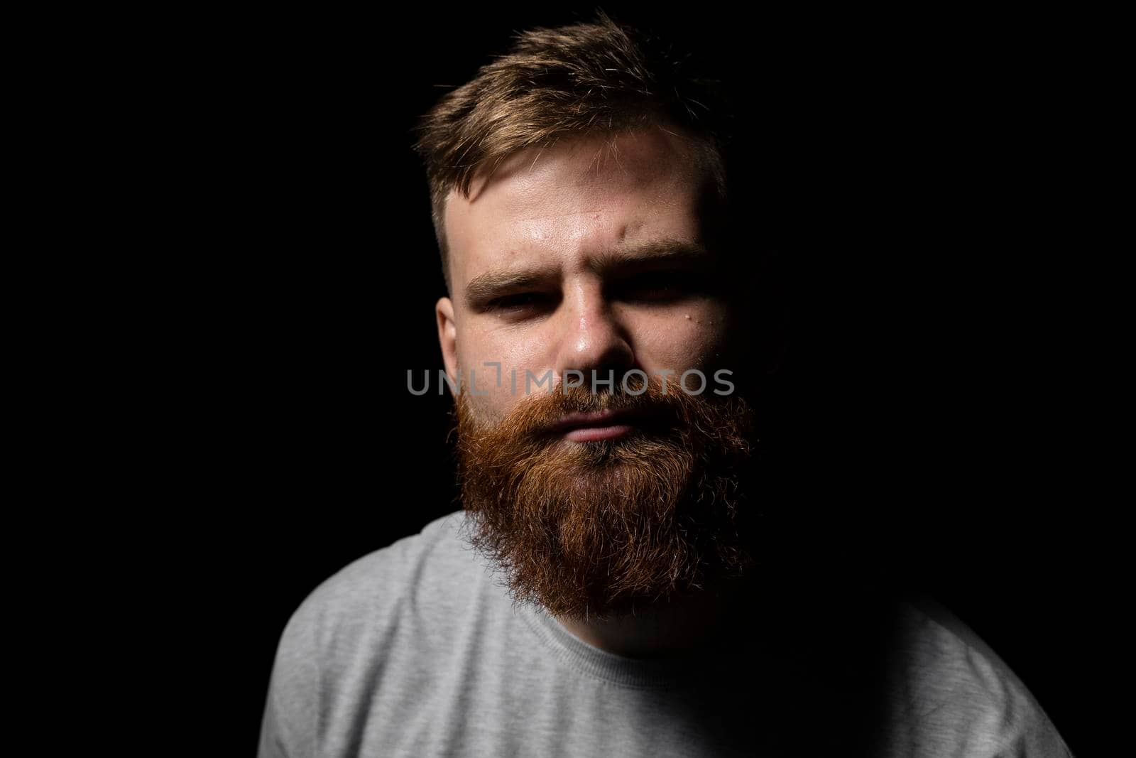 Close-up portrait of a handsome a brunette brutal bearded man in a grey t-shirt. Stylish and handsome man with a beard