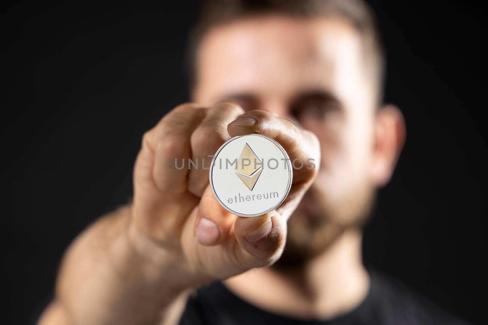 Young bearded man holding virtual currency ethereum coin. Cryptocurrency. by vovsht
