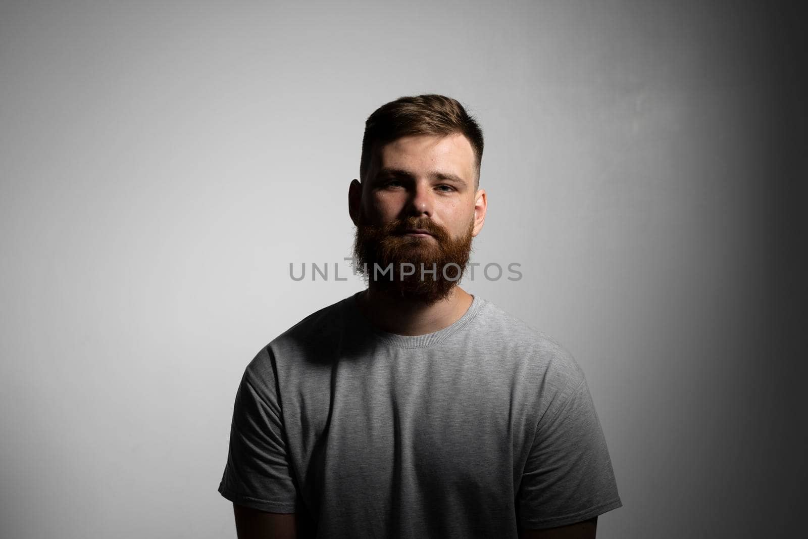 Close-up portrait of a handsome a brunette brutal bearded man in a grey t-shirt. Stylish and handsome man with a beard