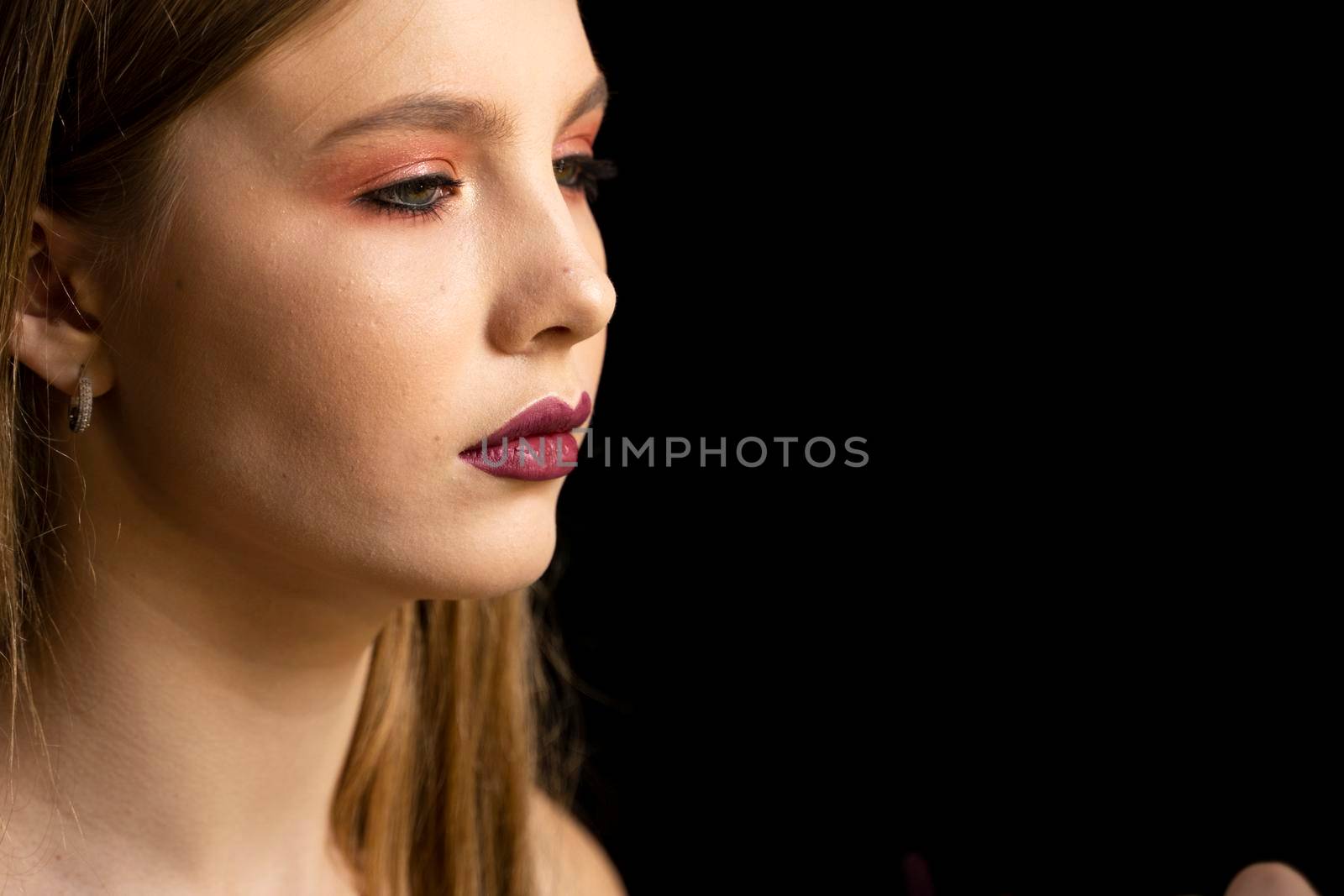 Makeup artist applies red lipstick on a beautiful woman face. Hand of make-up master, painting lips of young beauty model girl. Make up in process. by vovsht