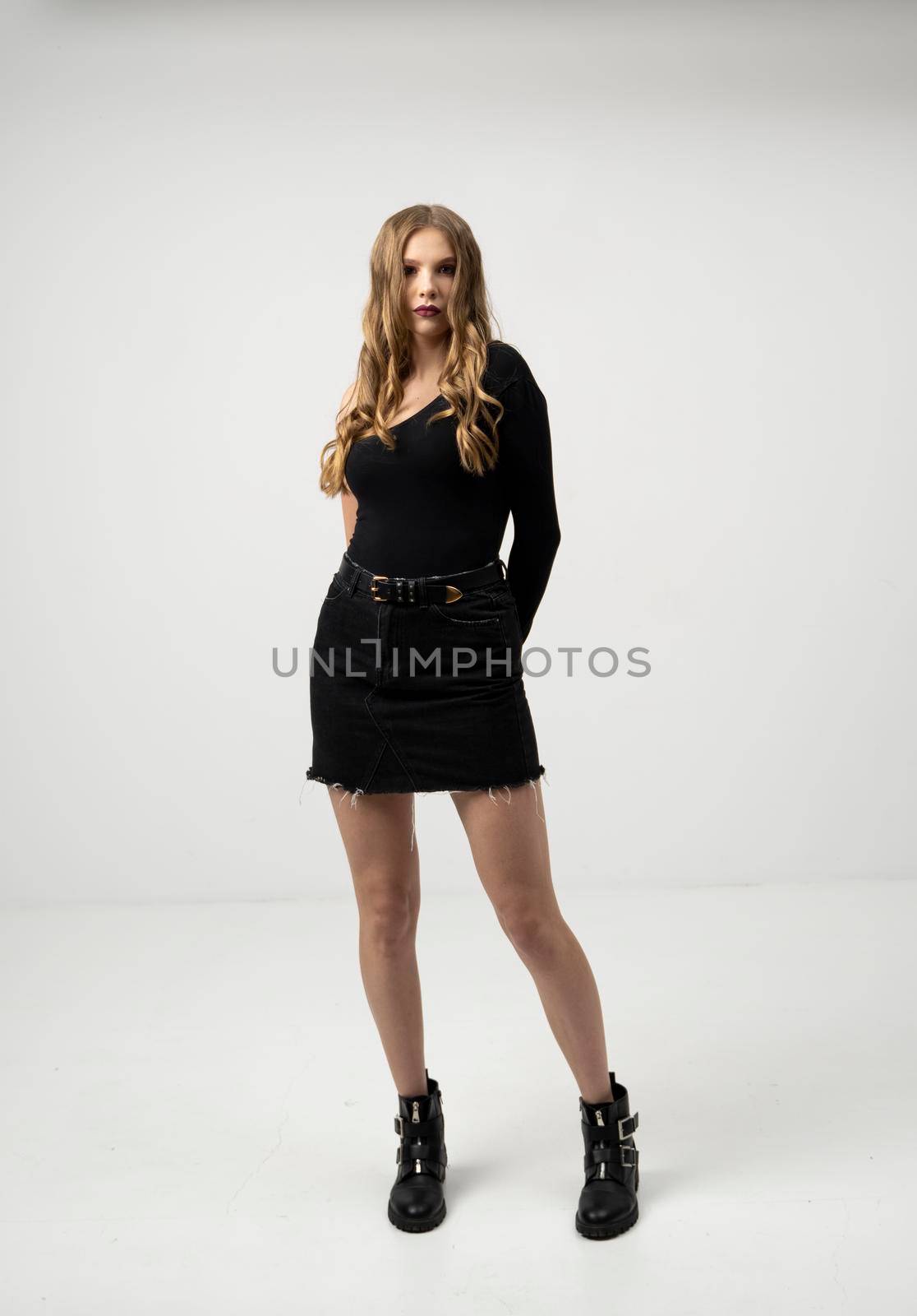 Beautiful young woman portrait in a black t-shirt and mini skirt. Studio shot, isolated on gray background