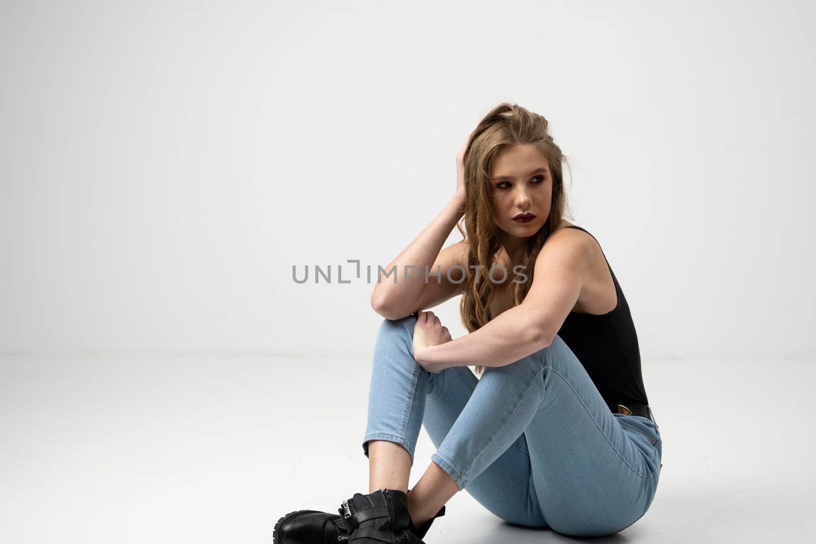 Beautiful young woman portrait in a black t-shirt and blue jeans. Studio shot, isolated on gray background