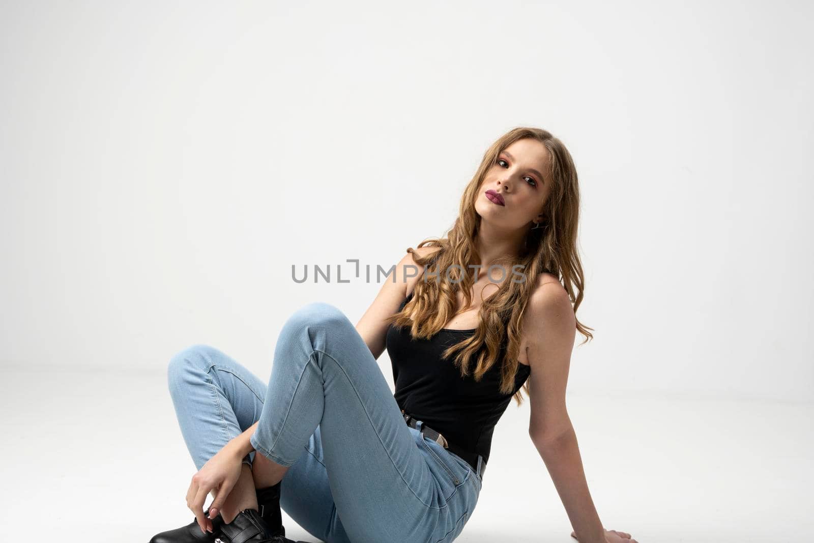 Beautiful young woman portrait in a black t-shirt and blue jeans. Studio shot, isolated on gray background