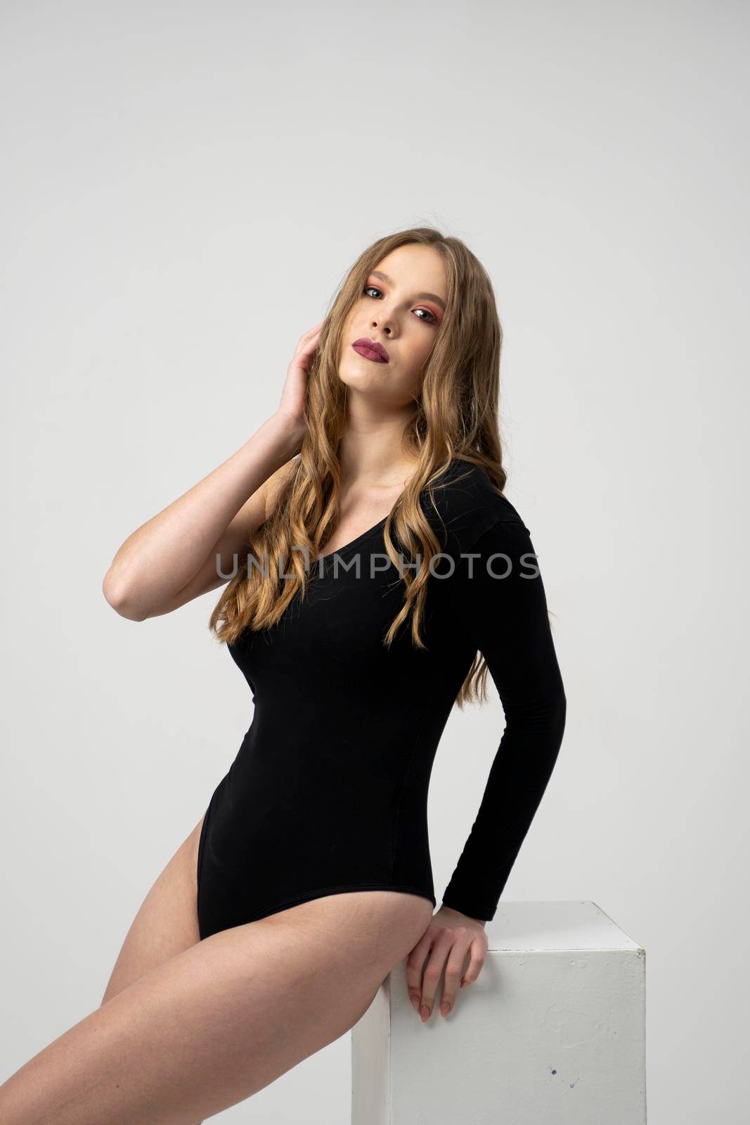 Beautiful young woman portrait in a black bodysuit. Studio shot, isolated on gray background. by vovsht