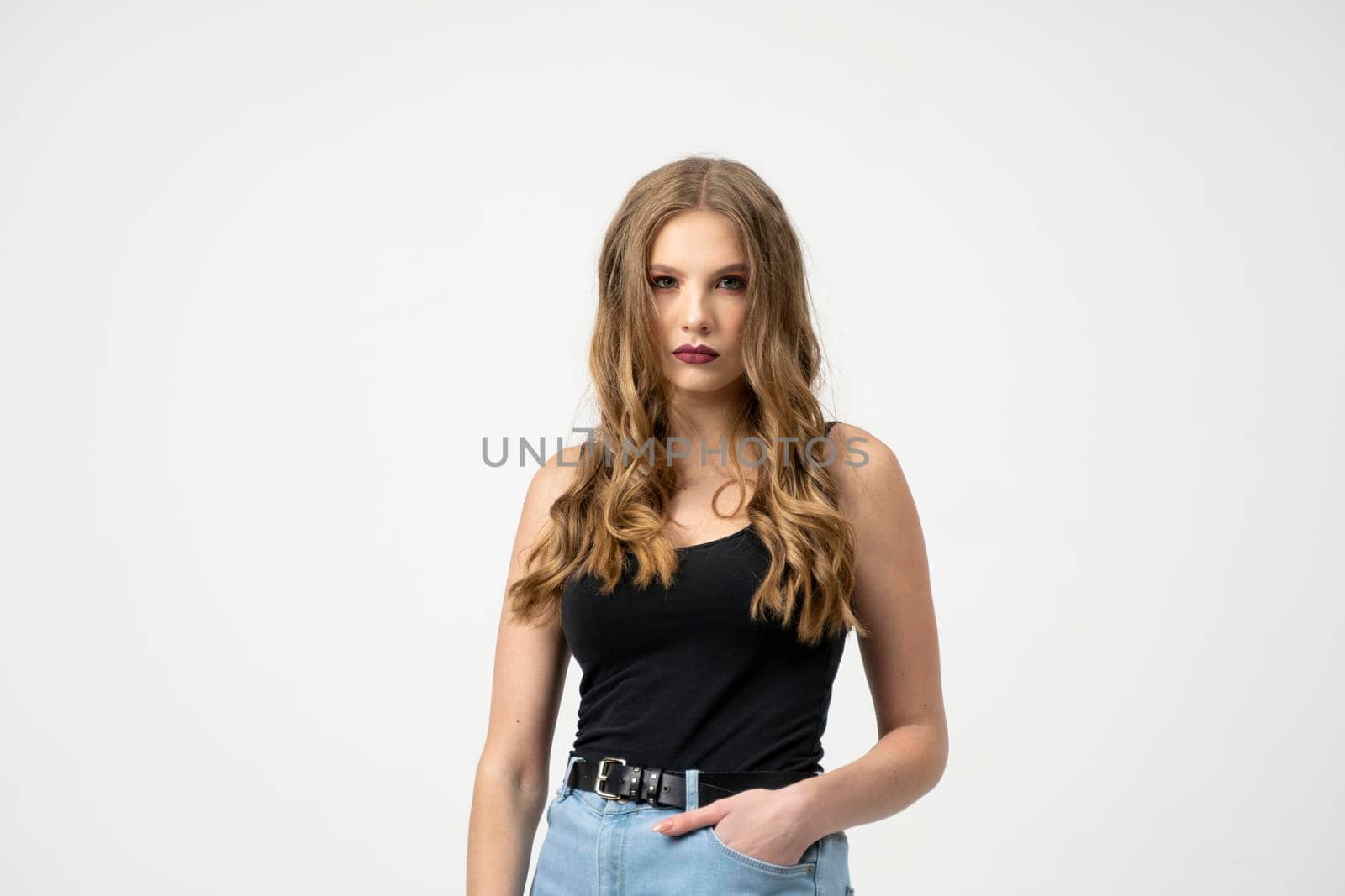 Beautiful young woman portrait in a black t-shirt and blue jeans. Studio shot, isolated on gray background