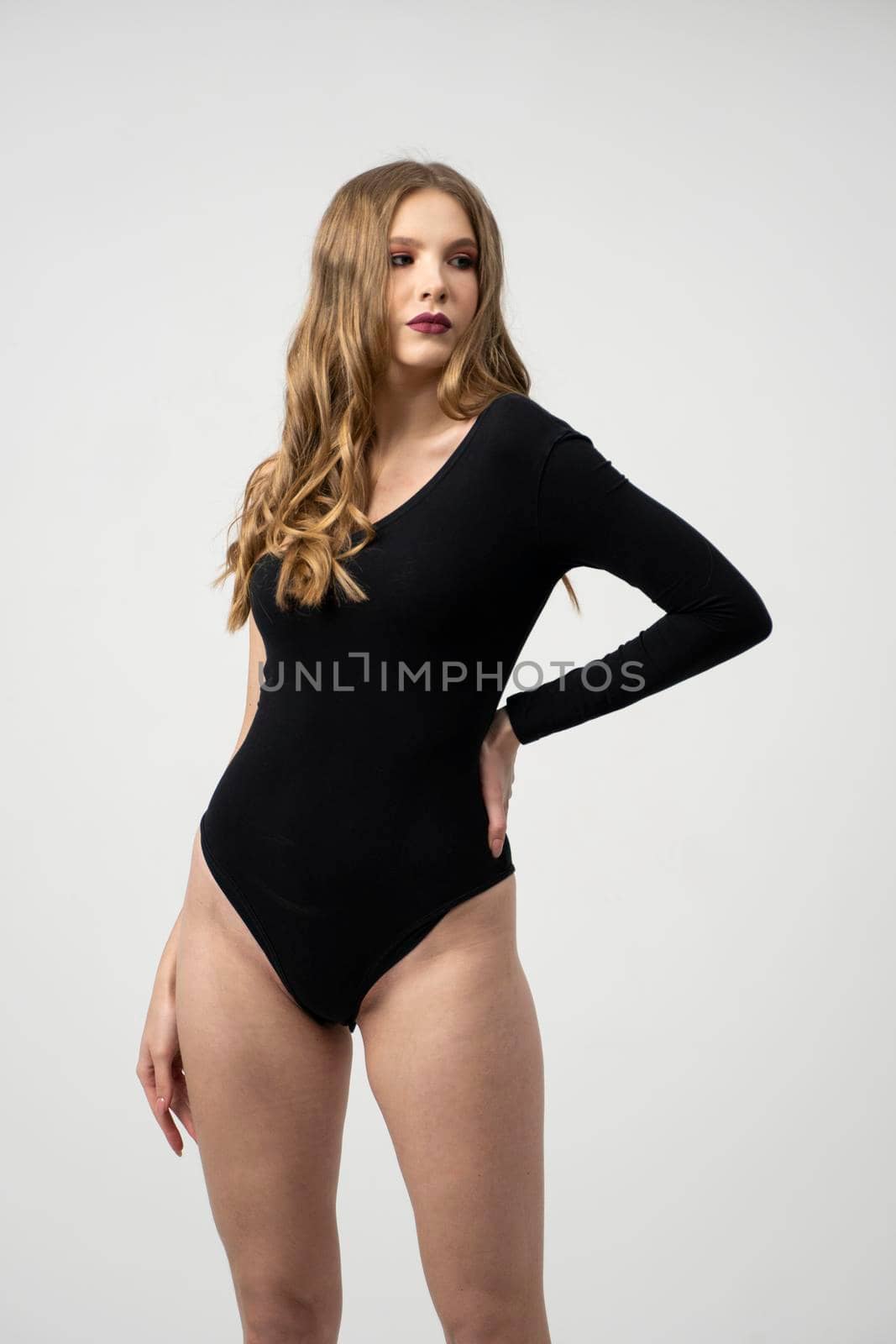 Beautiful young woman portrait in a black bodysuit. Studio shot, isolated on gray background