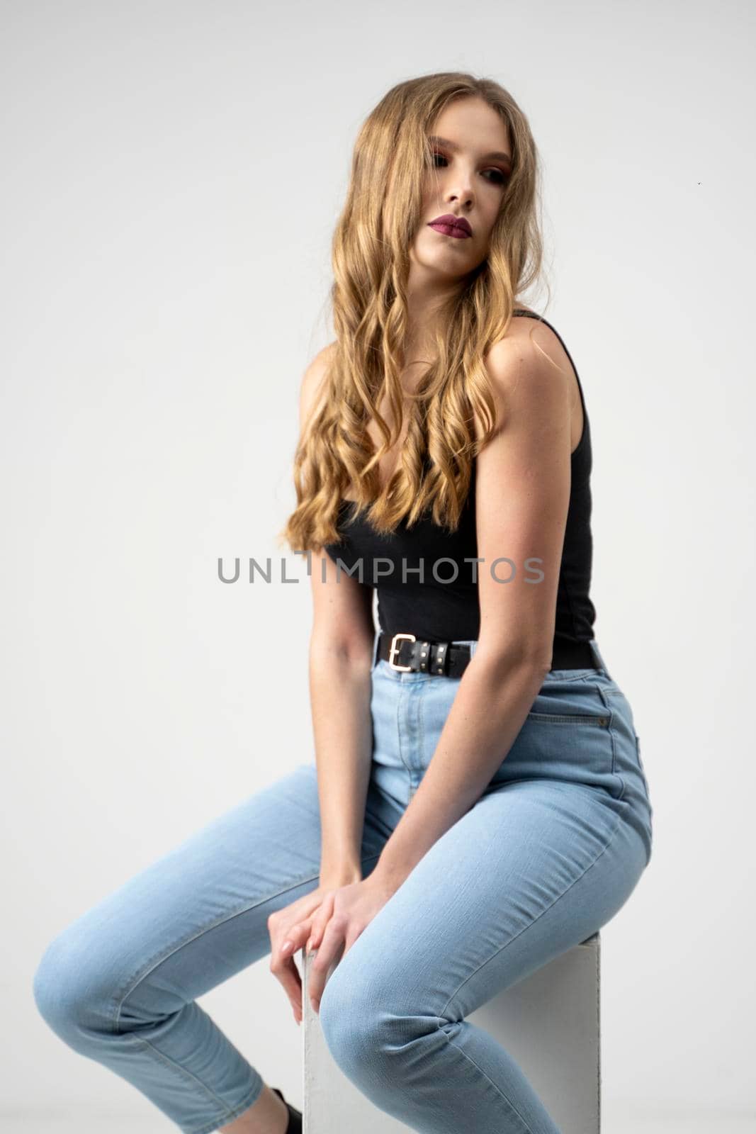 Beautiful young woman portrait in a black t-shirt and blue jeans. Studio shot, isolated on gray background. by vovsht