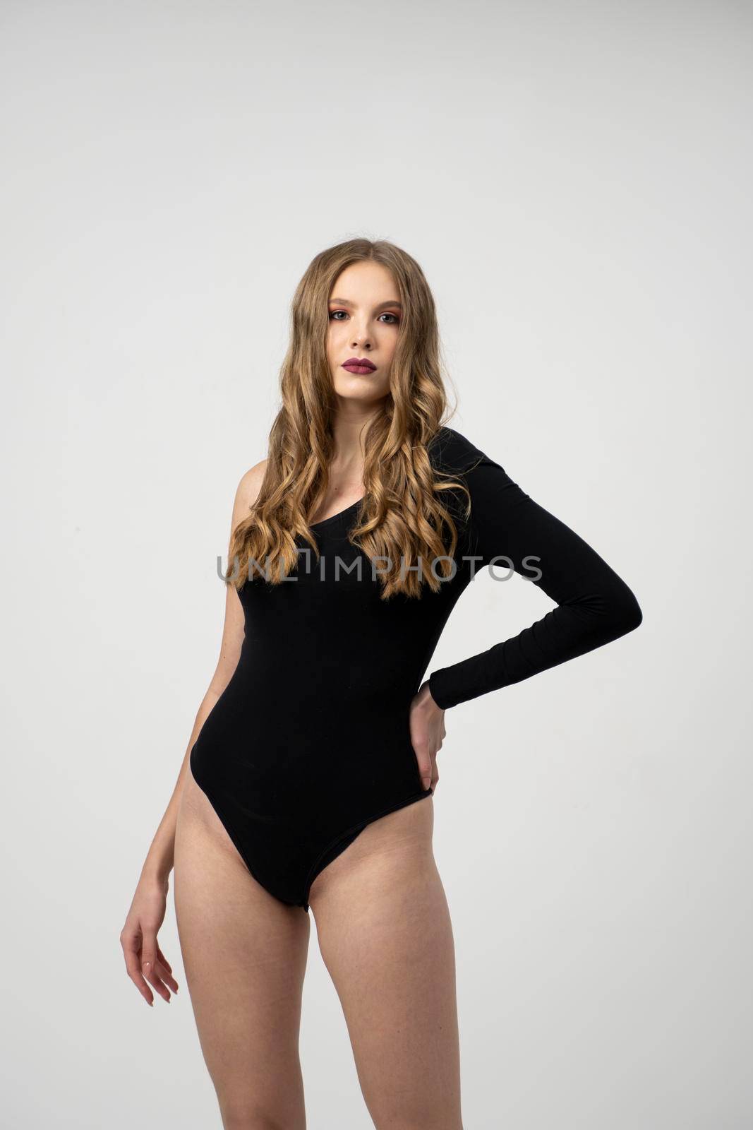 Beautiful young woman portrait in a black bodysuit. Studio shot, isolated on gray background. by vovsht
