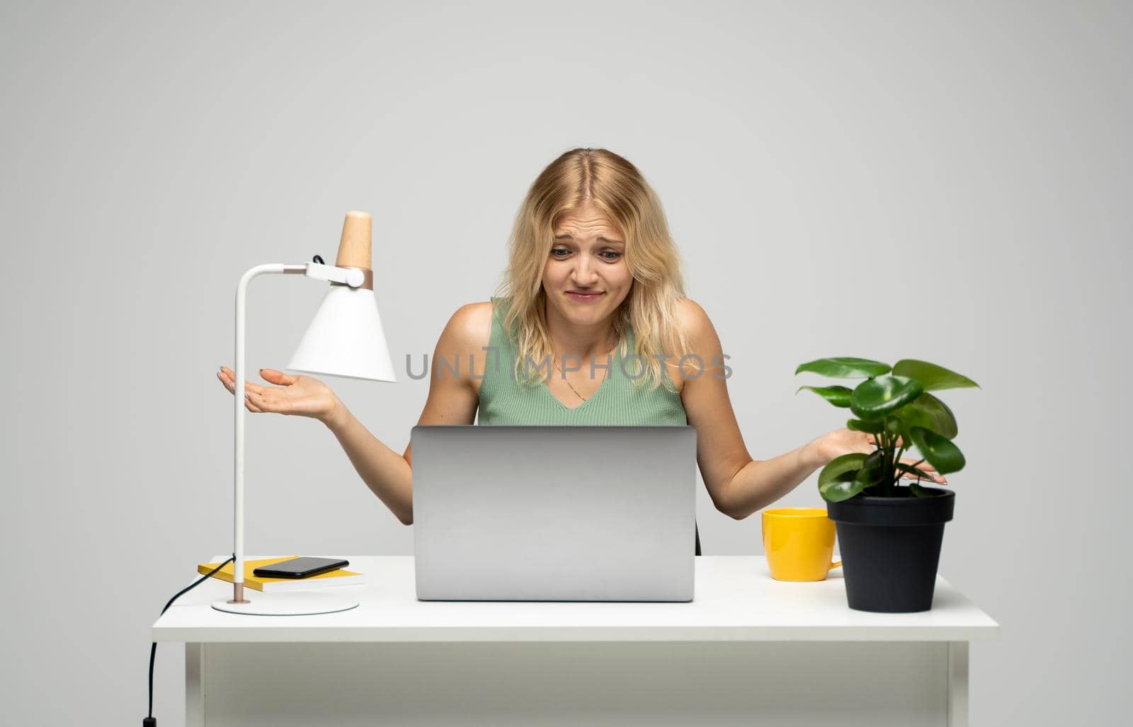 Confused blonde business woman working on a laptop on a white background. by vovsht