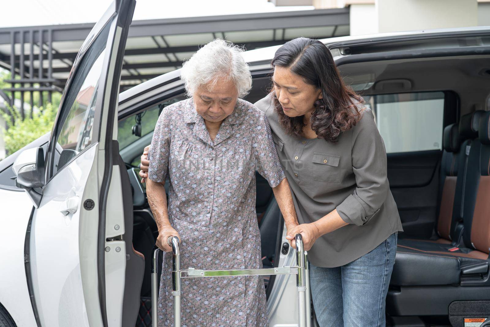 Help and support asian senior or elderly old lady woman patient walk with walker prepare get to her car, healthy strong medical concept. by pamai