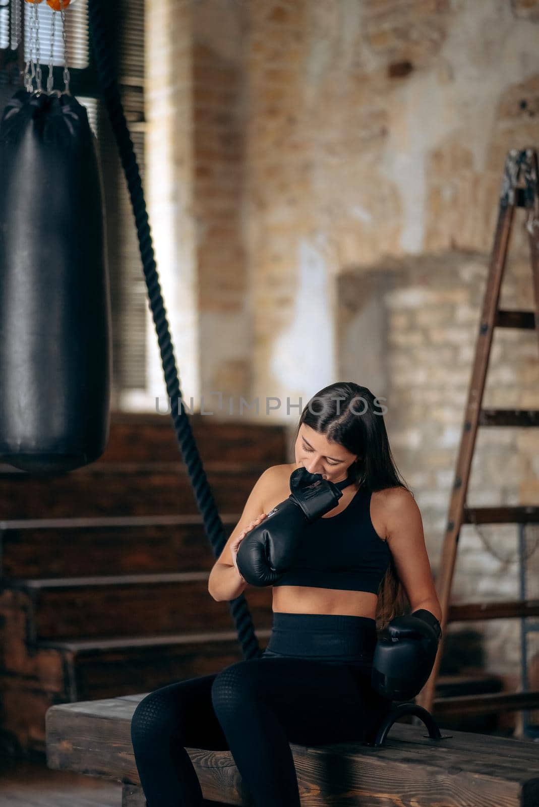 Beautiful confident young fitness girl taking off a boxing glove