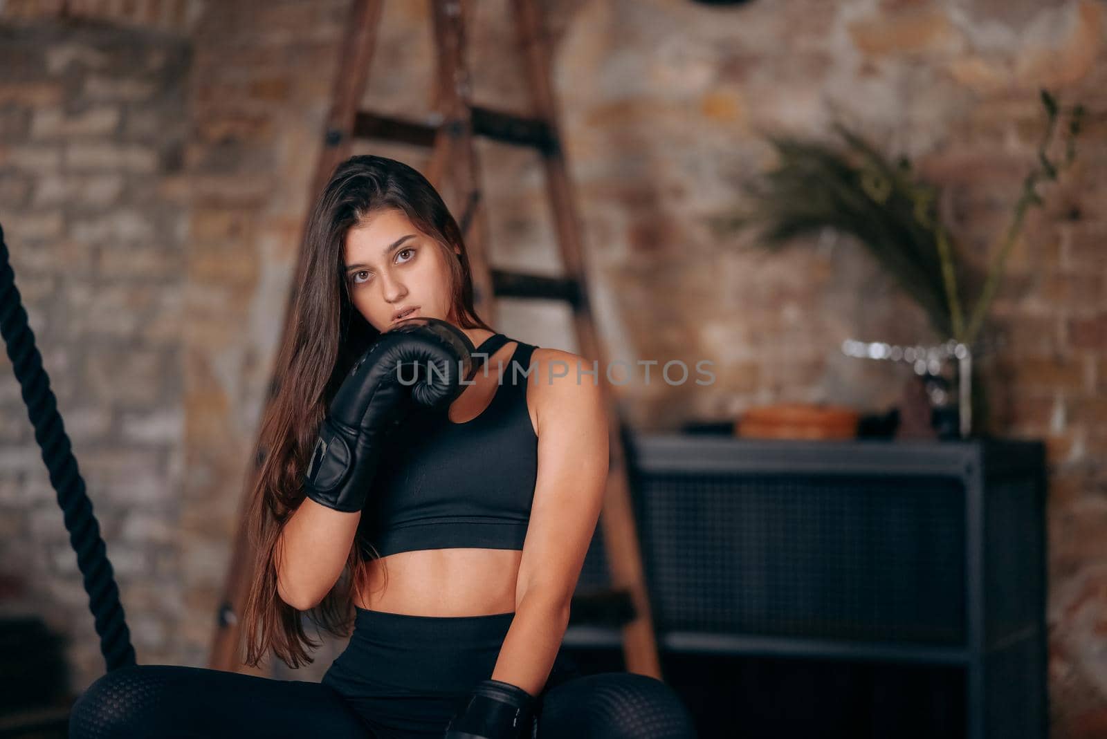Beautiful confident young fitness girl posing at camera in black boxing glove